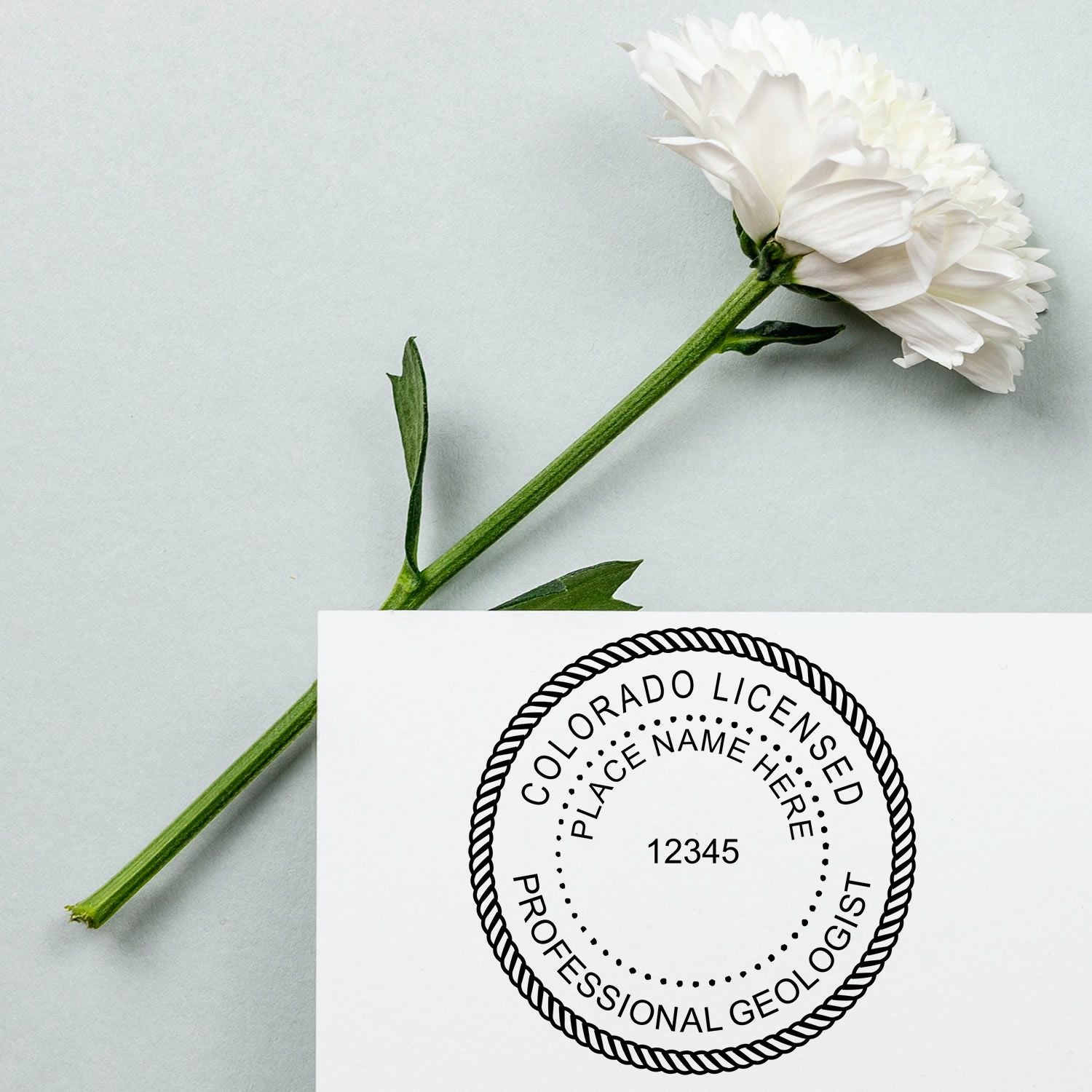 A lifestyle photo showing a stamped image of the Slim Pre-Inked Colorado Professional Geologist Seal Stamp on a piece of paper