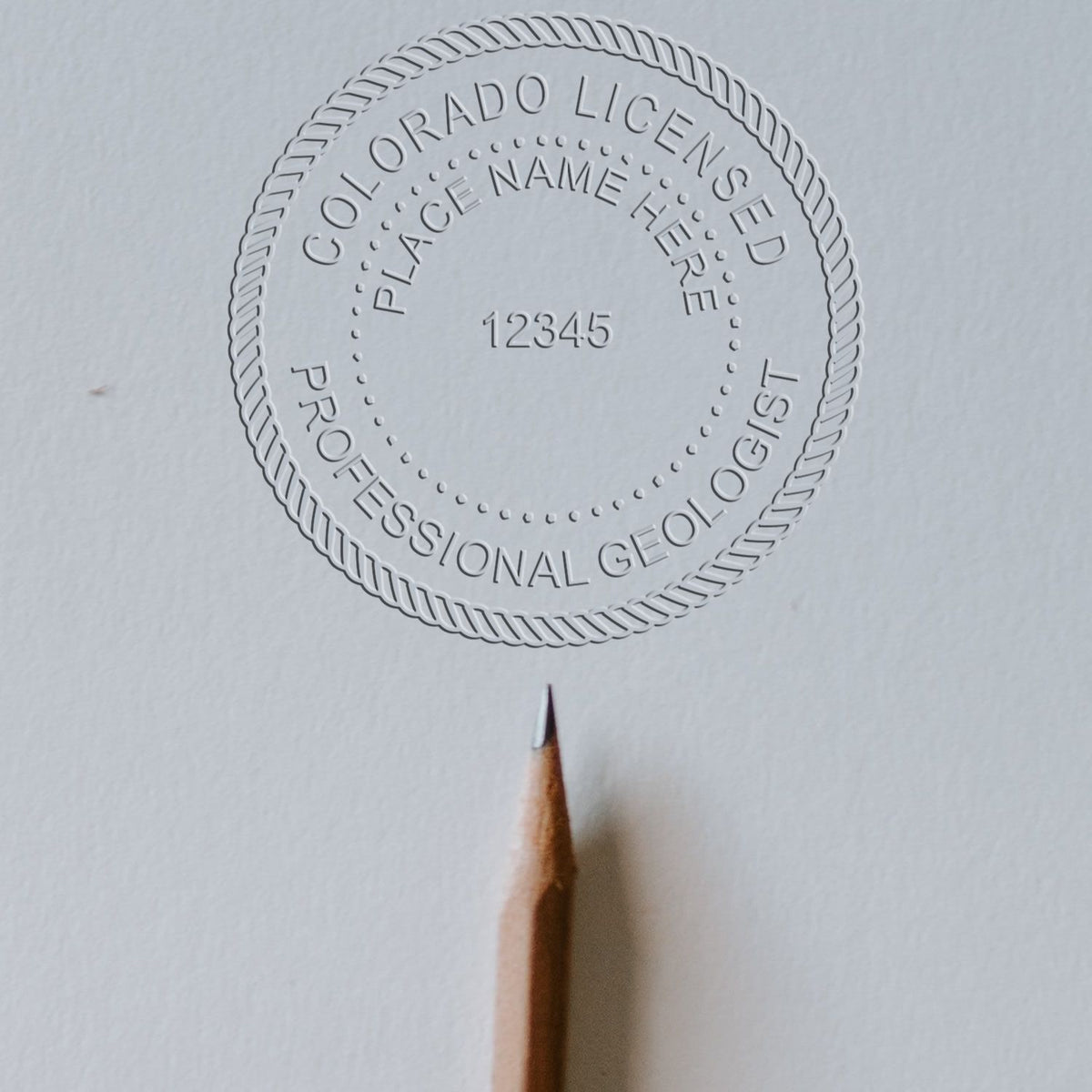 An alternative view of the Handheld Colorado Professional Geologist Embosser stamped on a sheet of paper showing the image in use