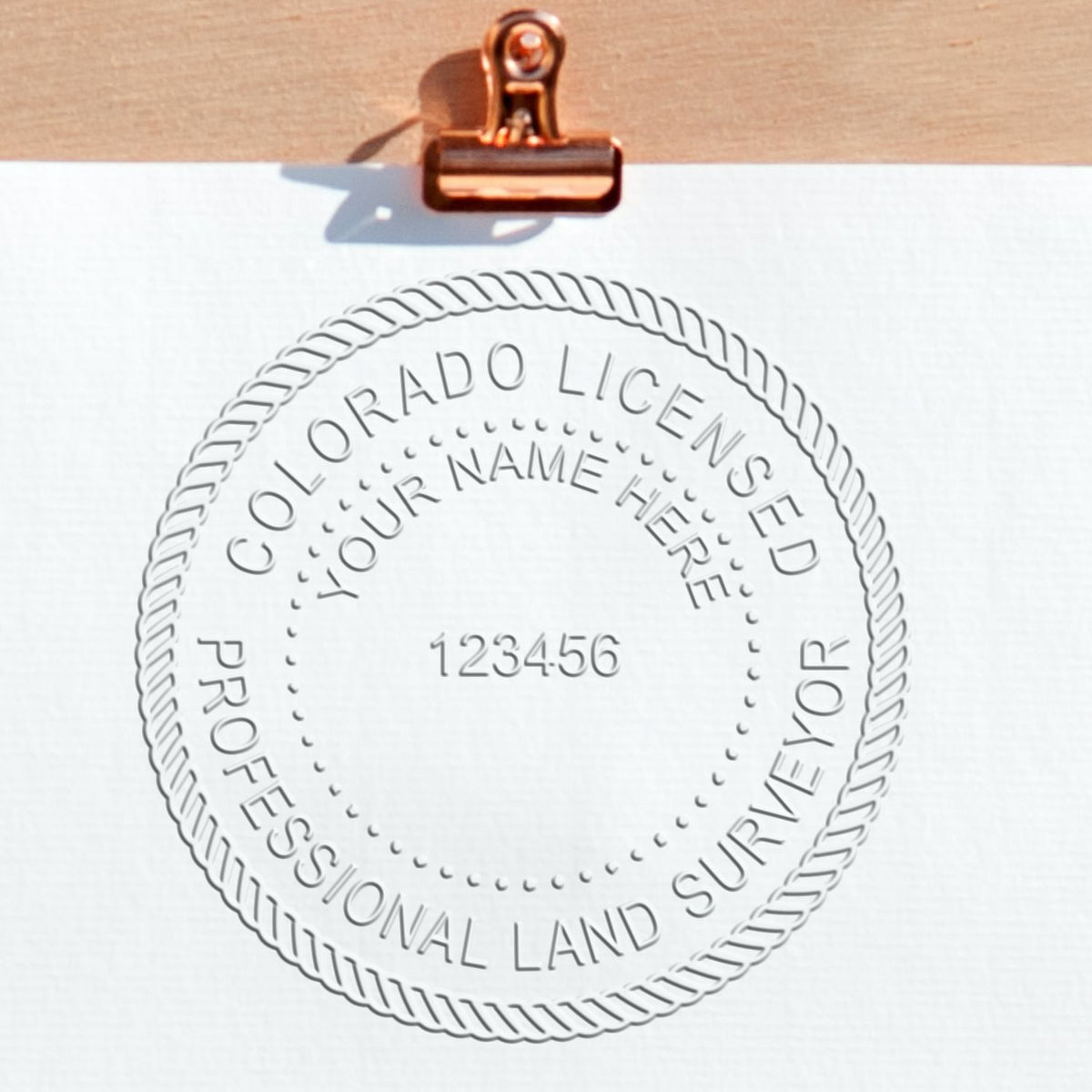 A lifestyle photo showing a stamped image of the State of Colorado Soft Land Surveyor Embossing Seal on a piece of paper