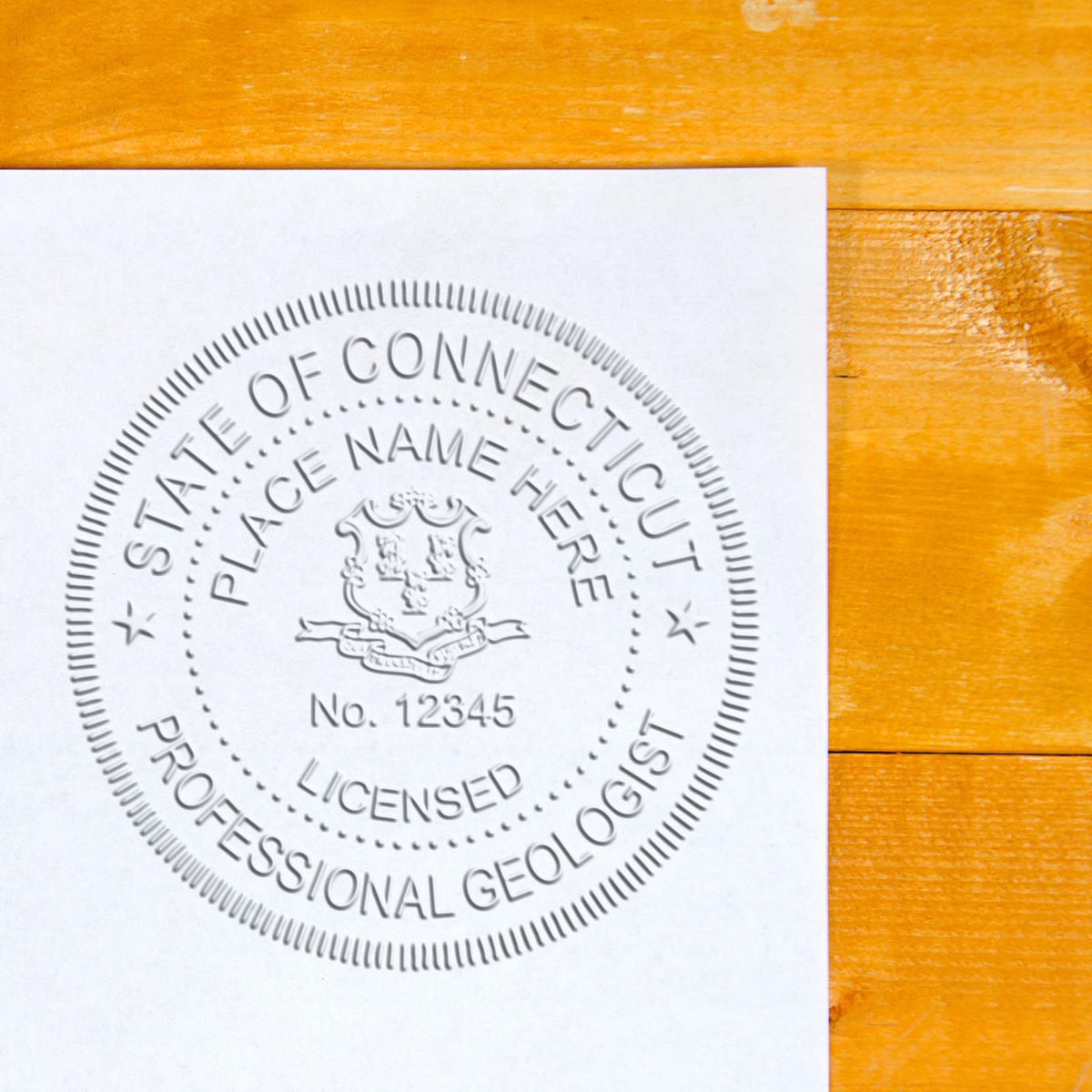 A lifestyle photo showing a stamped image of the Heavy Duty Cast Iron Connecticut Geologist Seal Embosser on a piece of paper