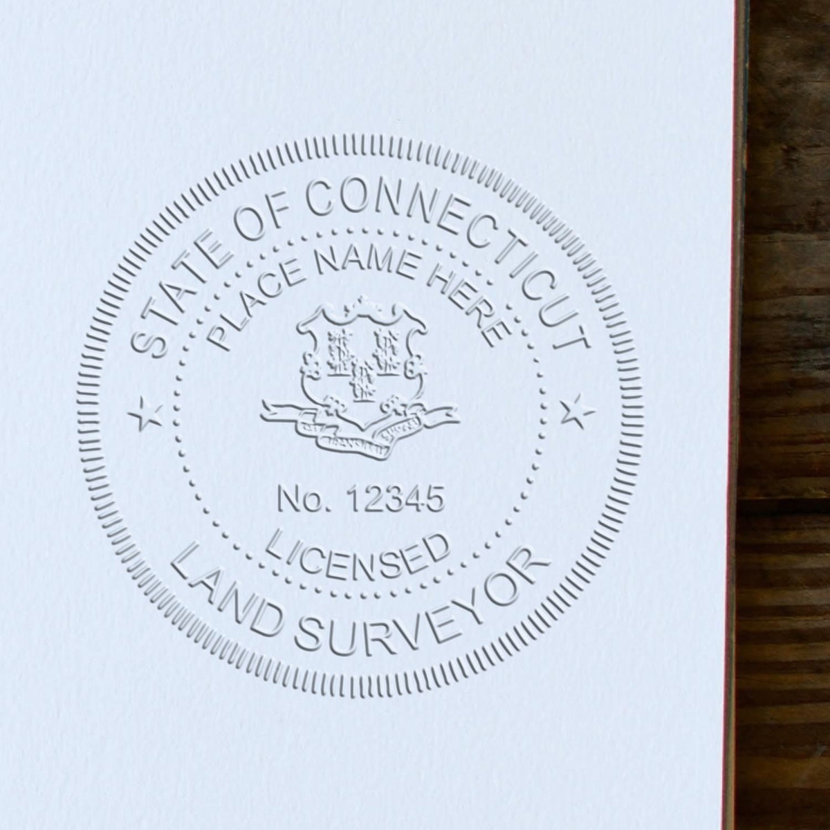 An in use photo of the Hybrid Connecticut Land Surveyor Seal showing a sample imprint on a cardstock