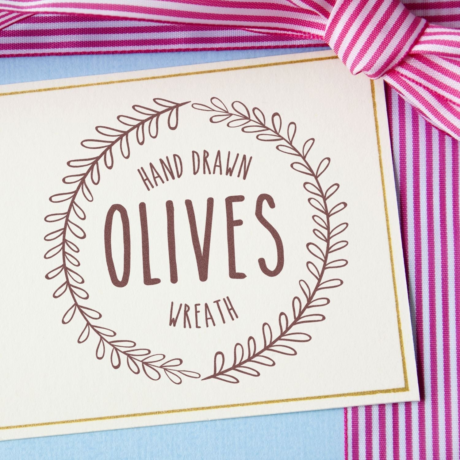 Custom Rubber Stamp Size 7 Inch Diameter used on a card with Hand Drawn Olives Wreath text, placed on a striped pink and white background.