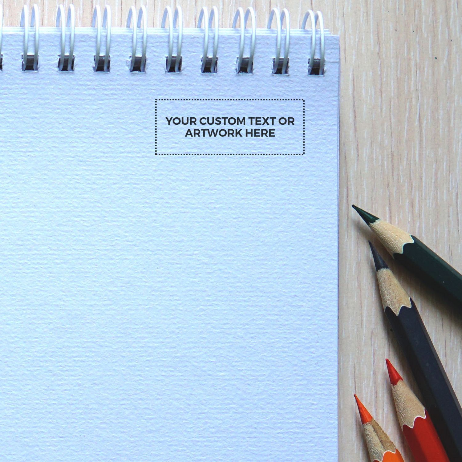 Custom Self Inking Stamp Trodat 4911 Size 9/16 x 1-1/2 on a spiral notebook with colored pencils beside it.