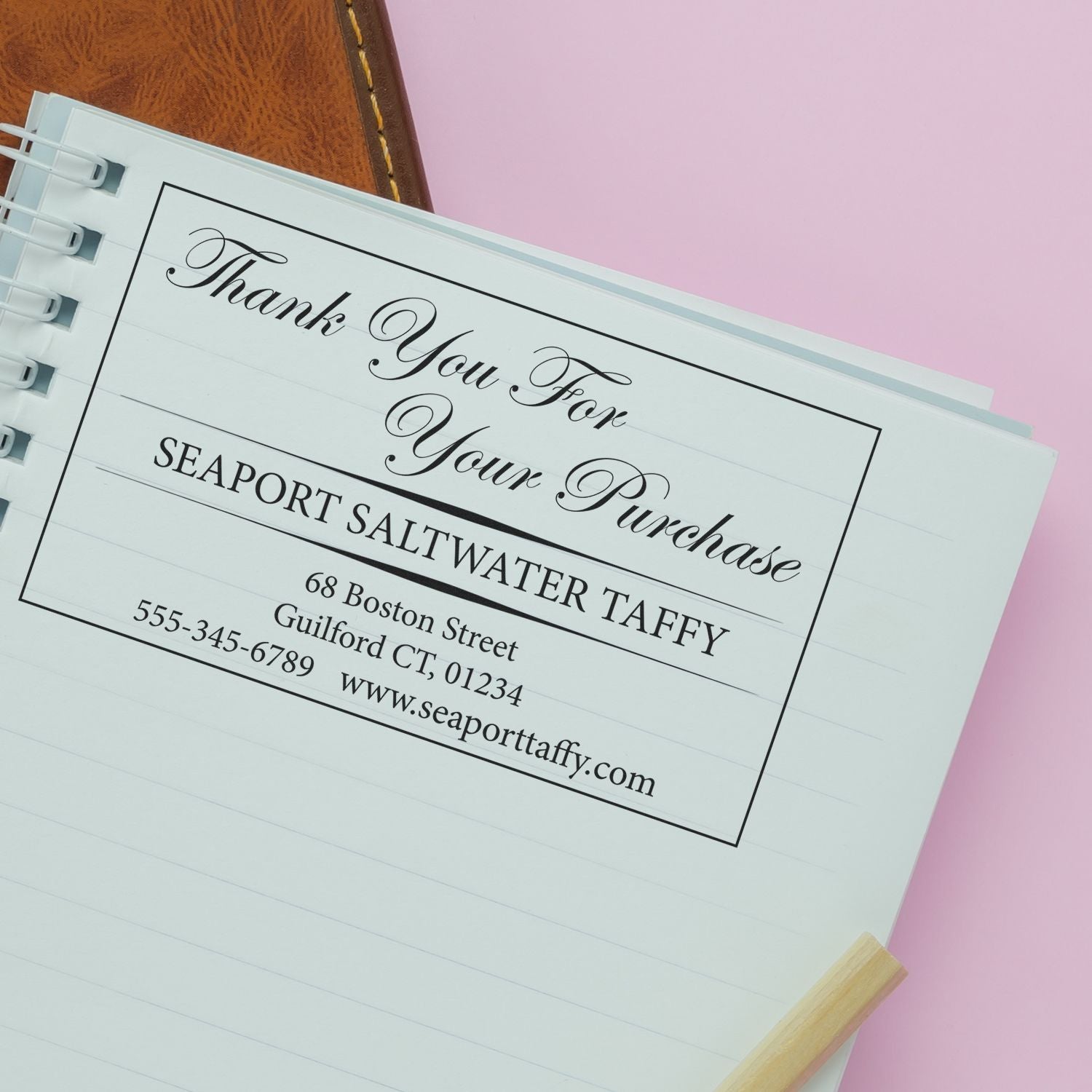 Custom Rubber Stamp Size 3 x 7 used on a notebook page, displaying a thank you message for Seaport Saltwater Taffy with contact details.