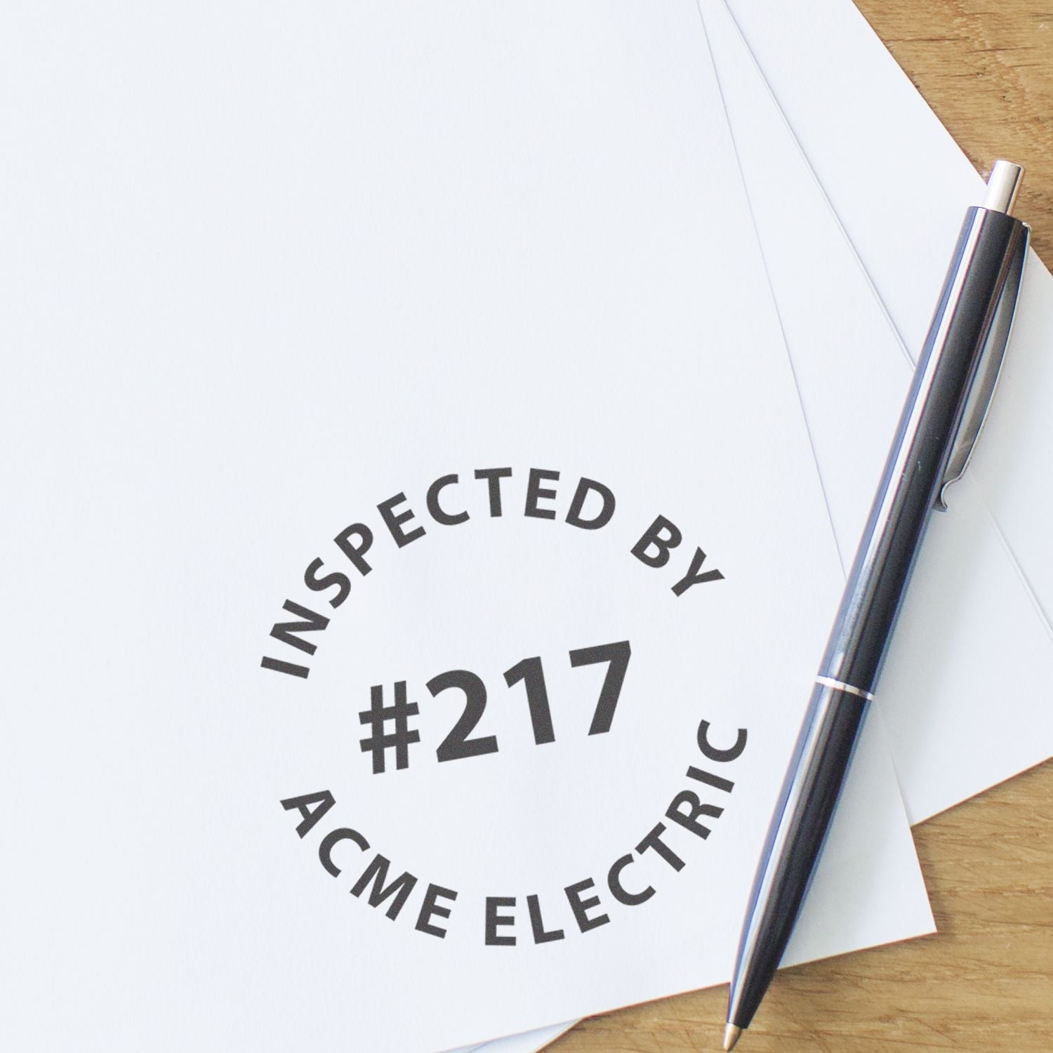 Custom Self Inking Stamp Trodat 4642 Size 1-5/8 Diameter used to stamp Inspected by #217 ACME Electric on white paper next to a pen.