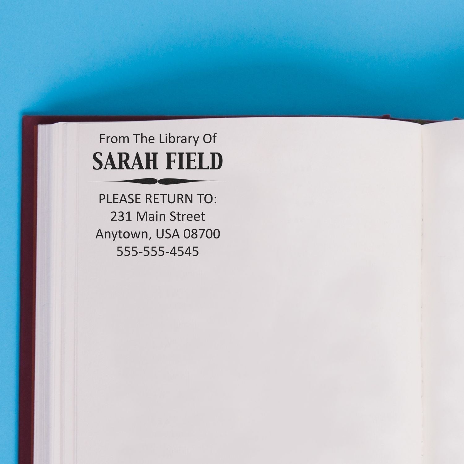 Open book stamped with From The Library Of SARAH FIELD using Custom Rubber Stamp Size 2 x 2, showing return address and phone number.