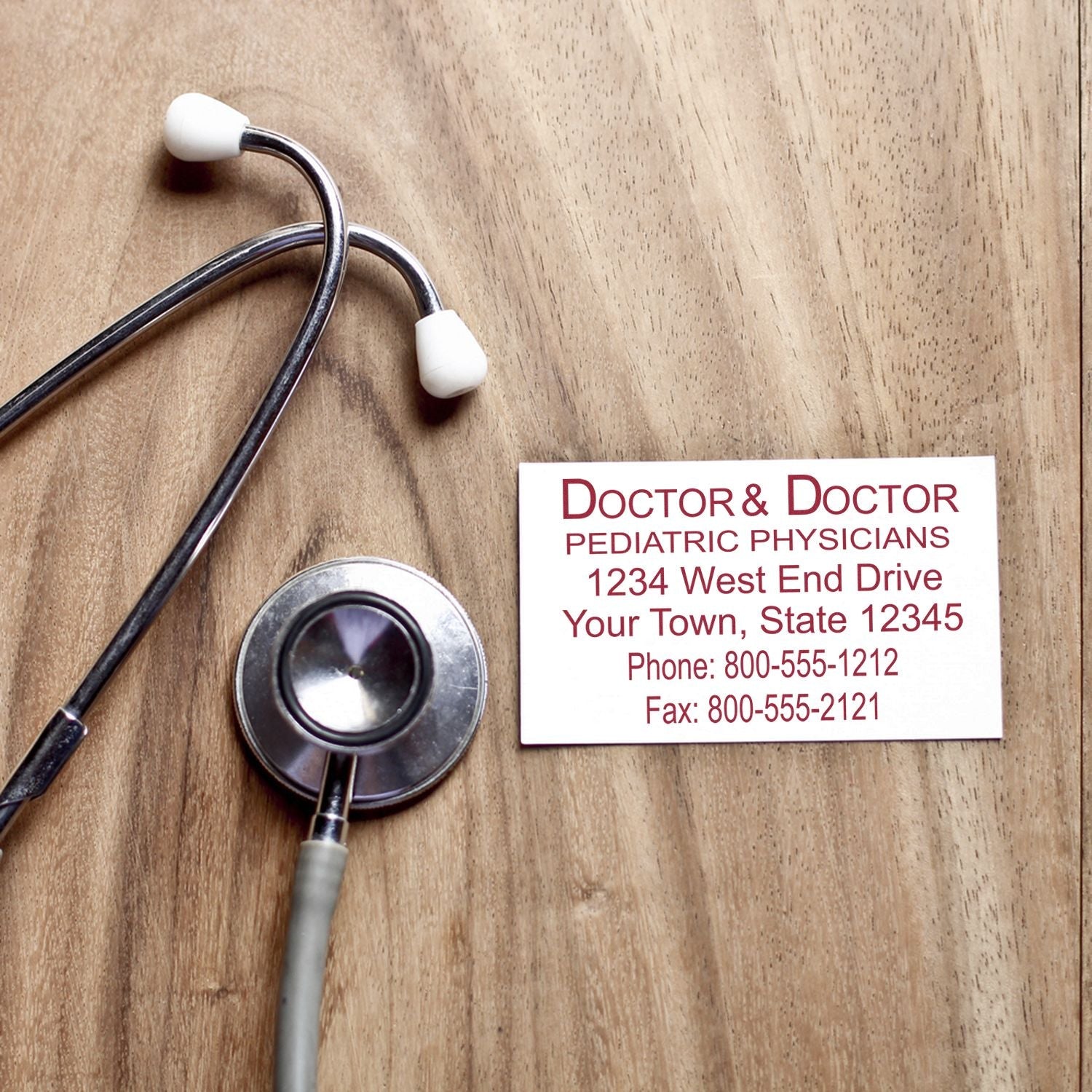 A 6 Line Custom Rubber Stamp with Wood Handle imprint on a business card next to a stethoscope on a wooden surface.