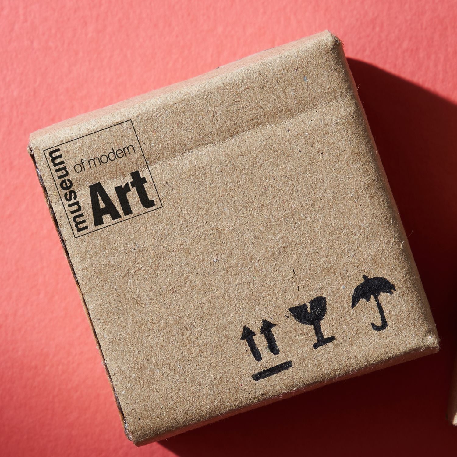 A cardboard box stamped with museum of modern Art using the Custom Self Inking Stamp Trodat 4921 Size 1/2 x 1/2 on a red background.