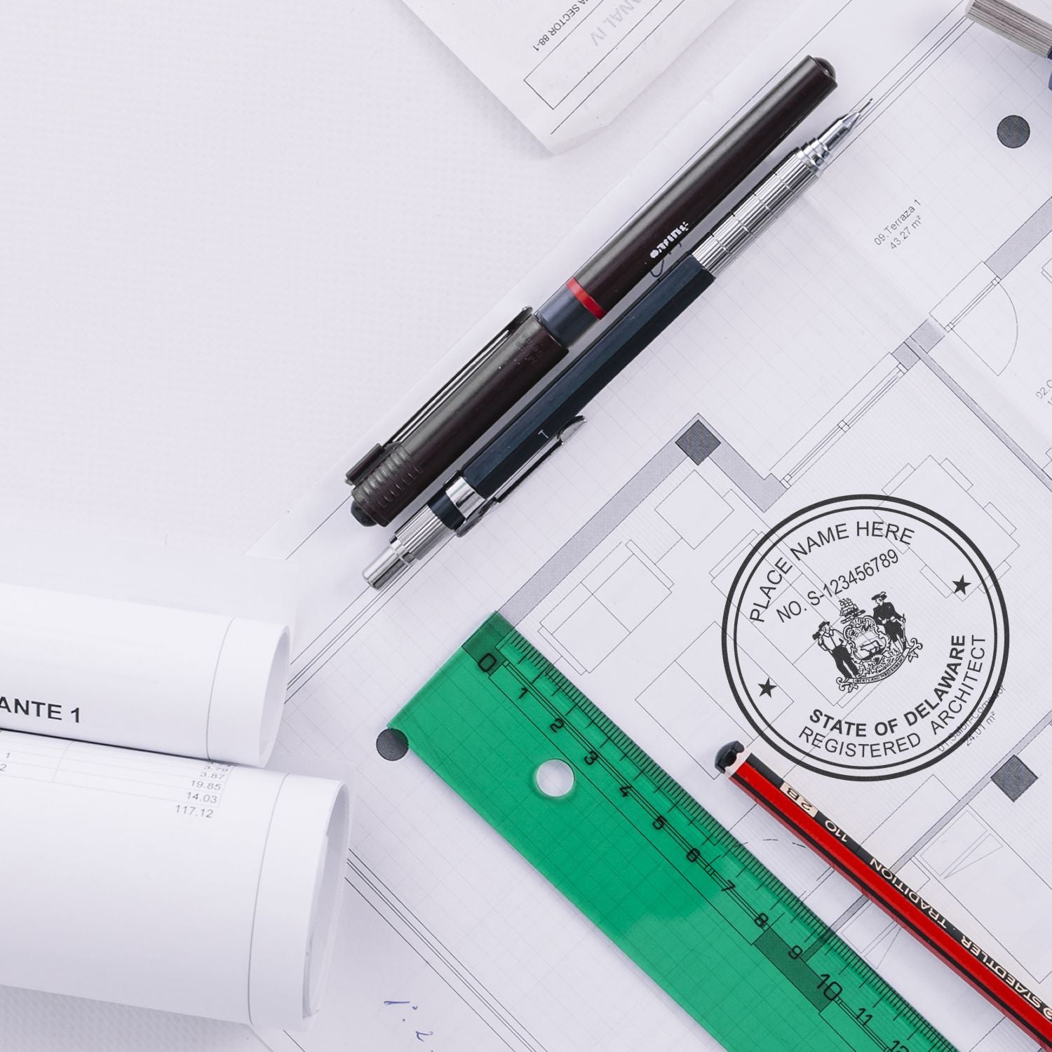 Architectural plans with a Delaware Architect Seal Stamp, pens, ruler, and rolled blueprints on a white surface.