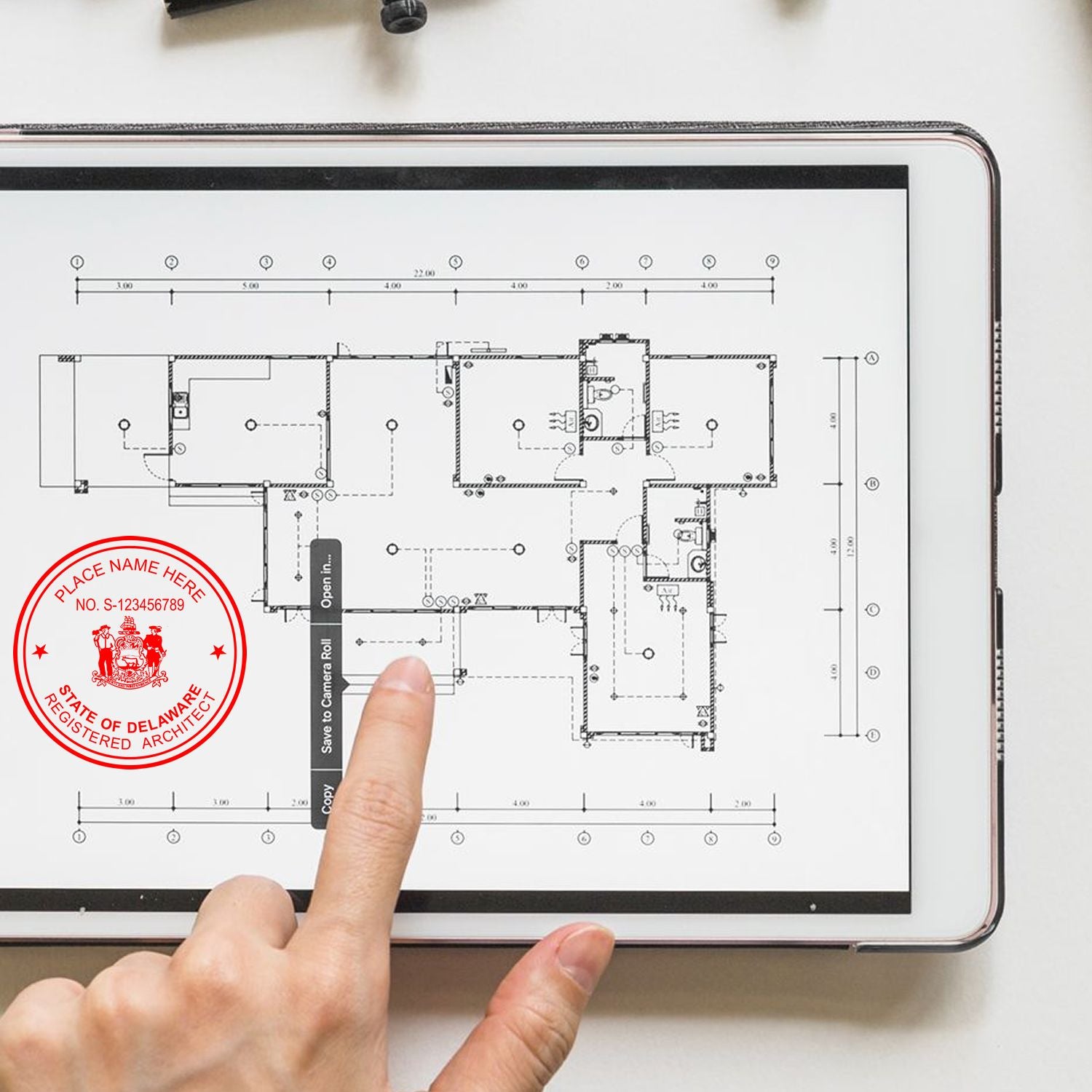 Person using Premium MaxLight Pre-Inked Delaware Architectural Stamp on a tablet displaying architectural plans.