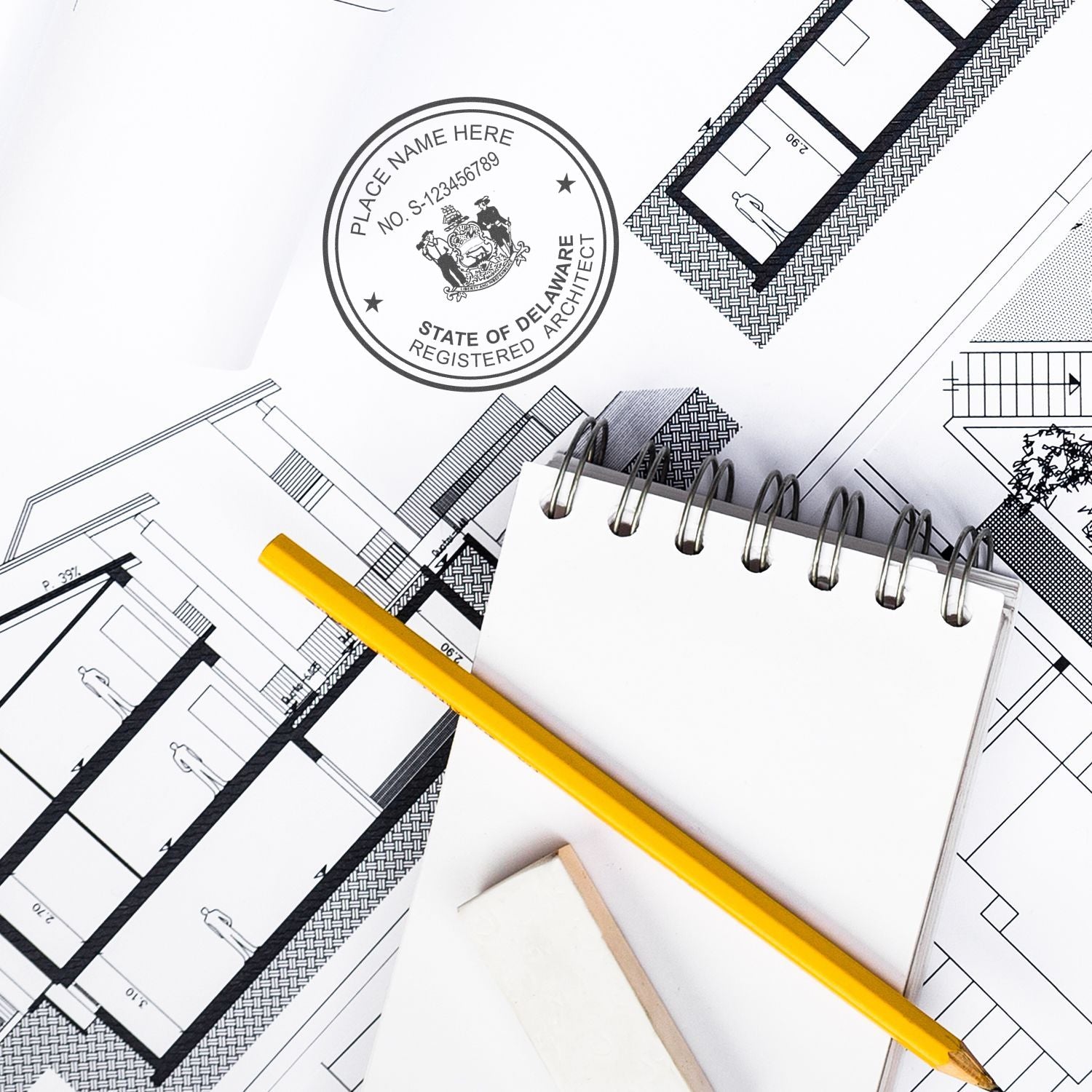 Self Inking Delaware Architect Stamp on architectural blueprints with a yellow pencil, notepad, and eraser nearby.