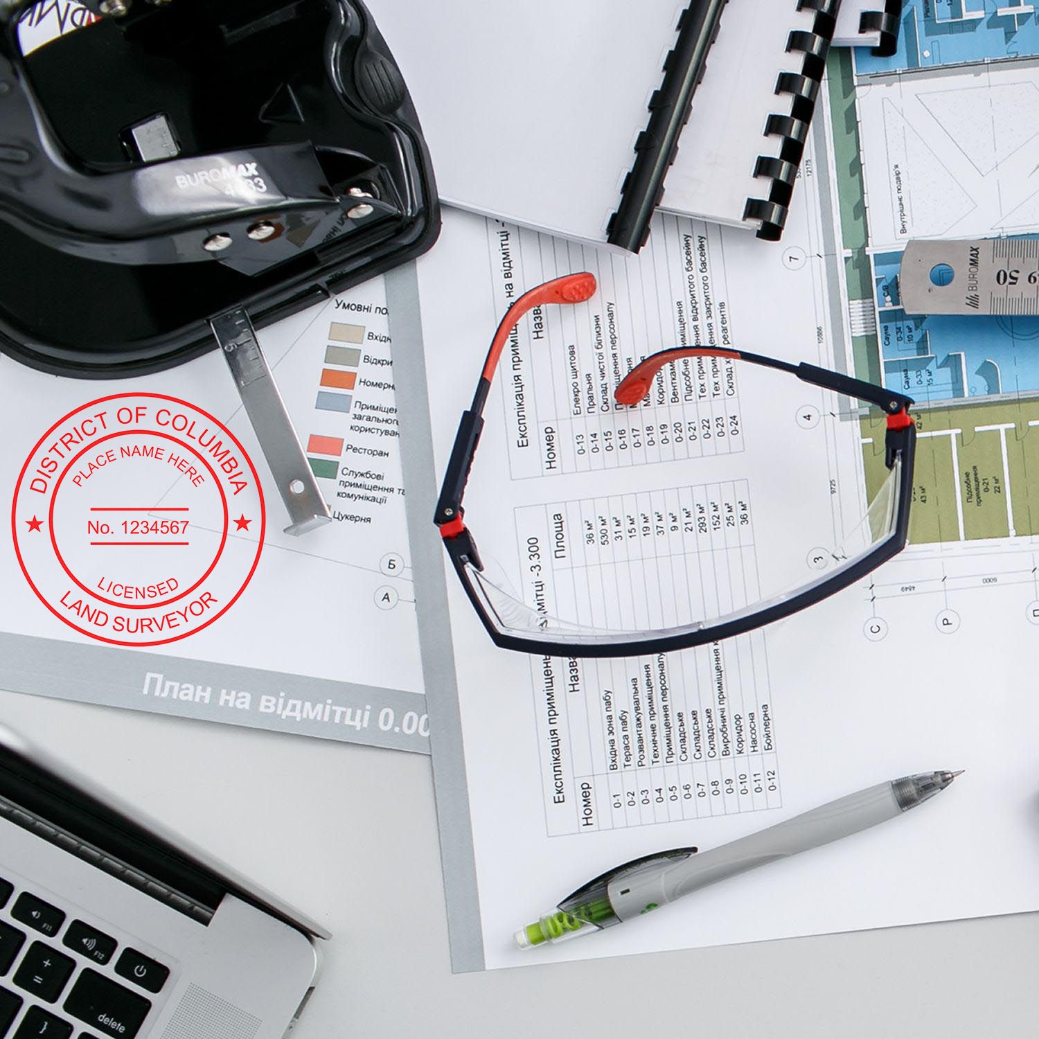 Desk with Digital District of Columbia Land Surveyor Stamp, Electronic Seal for DC Land Surveyor, glasses, pen, and documents.