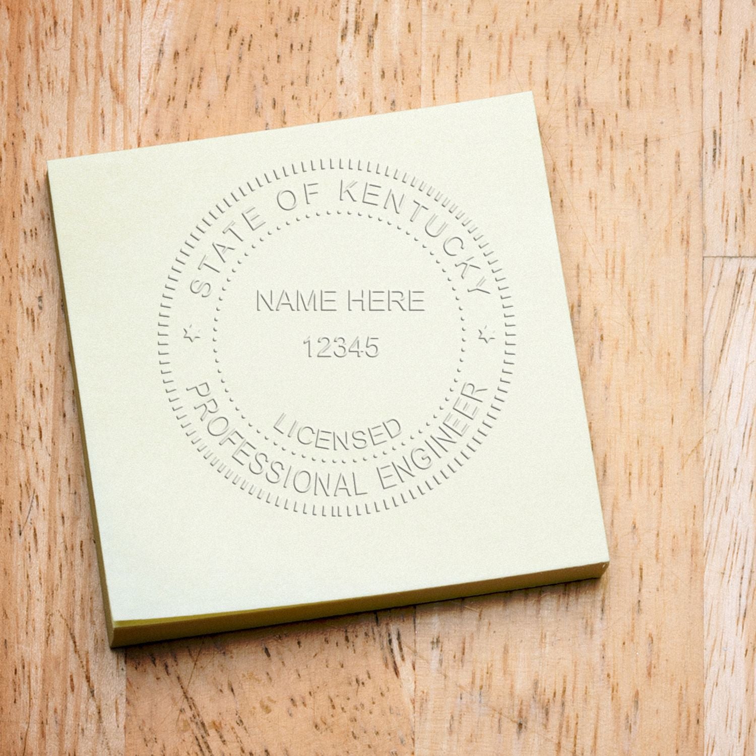 A Professional Engineer Black Gift Seal Embosser imprint on a yellow sticky note, displaying a circular seal with the text 'State of Kentucky, Licensed Professional Engineer' and placeholder for name and number.