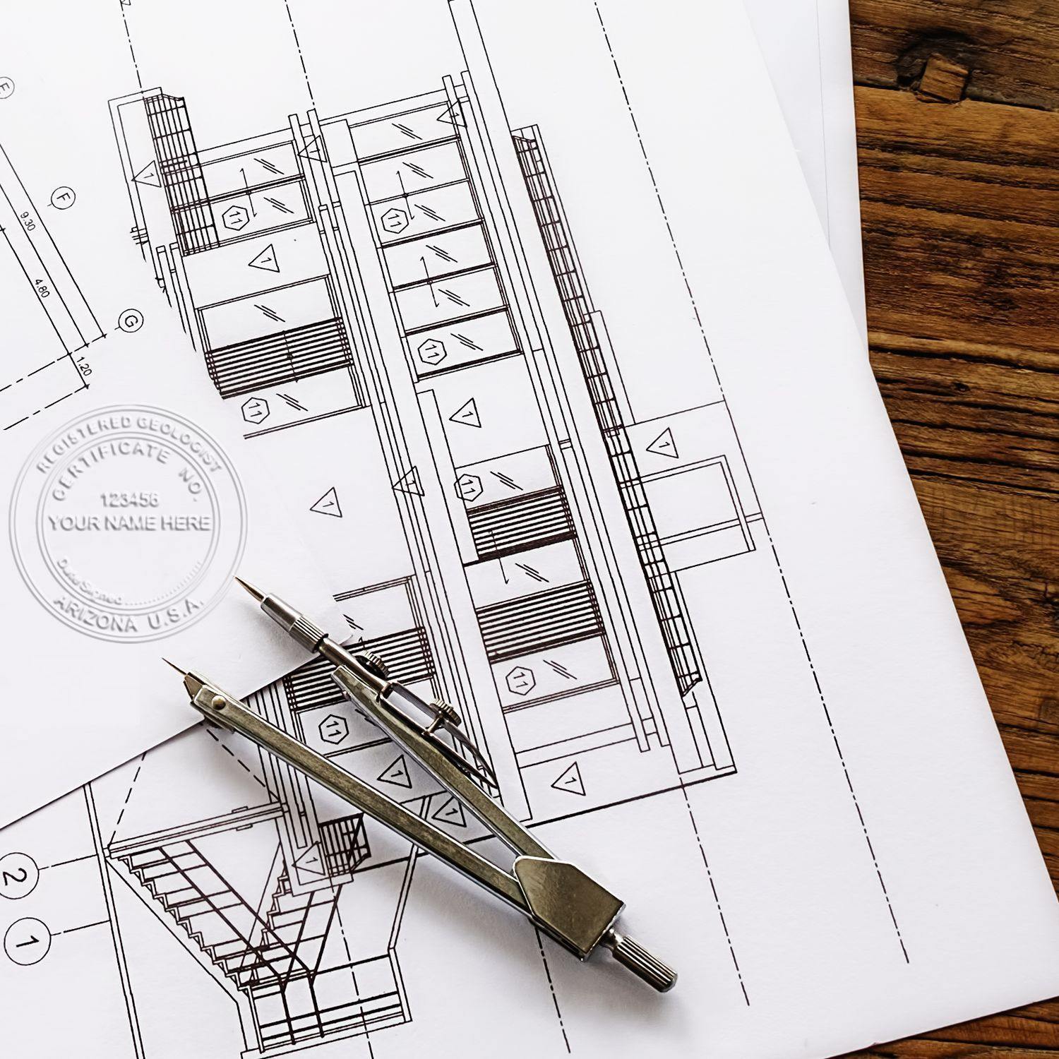 Geologist Pink Hybrid Handheld Embosser used on a certificate over architectural blueprints with a compass tool nearby on a wooden table.