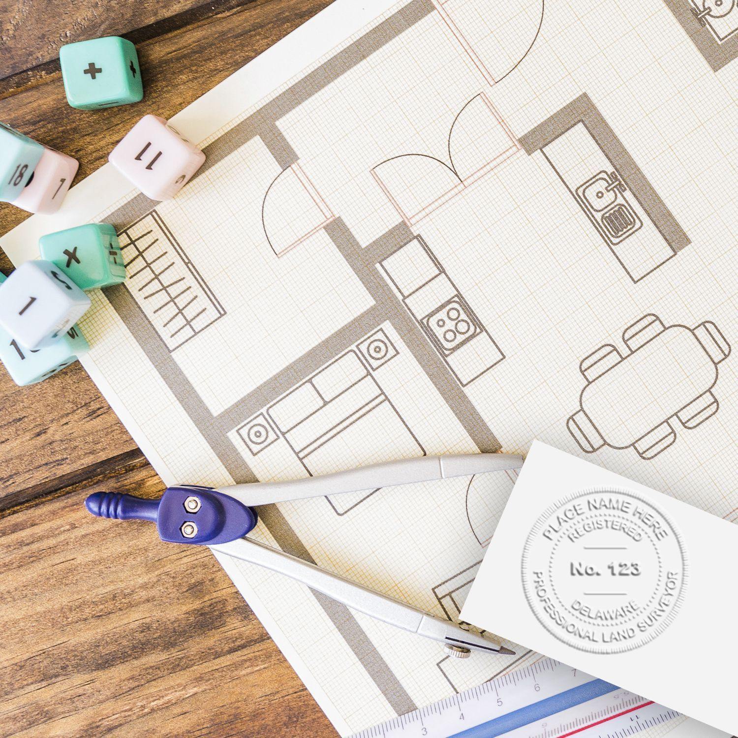 Land Surveyor Desk Seal Embosser in use on a floor plan, with drafting tools and dice nearby on a wooden desk.