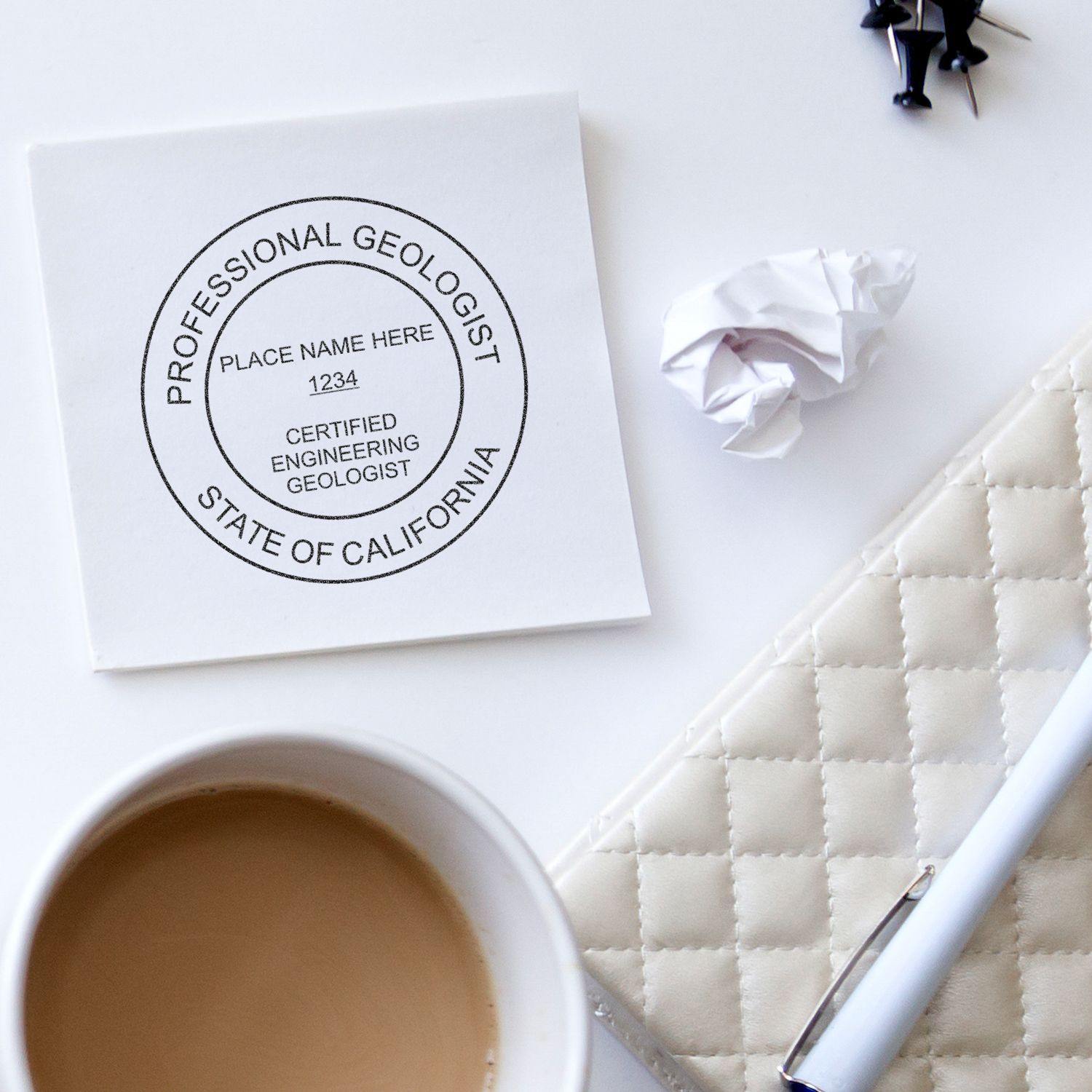 Engineering Geologist Self Inking Rubber Stamp of Seal on a white paper, next to a coffee cup, pen, and crumpled paper.