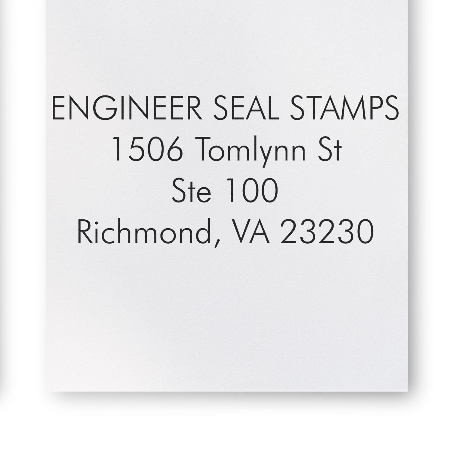 4 Line Address Stamp Regular Rubber Stamp in use, displaying ENGINEER SEAL STAMPS, 1506 Tomlynn St, Ste 100, Richmond, VA 23230 on white paper.