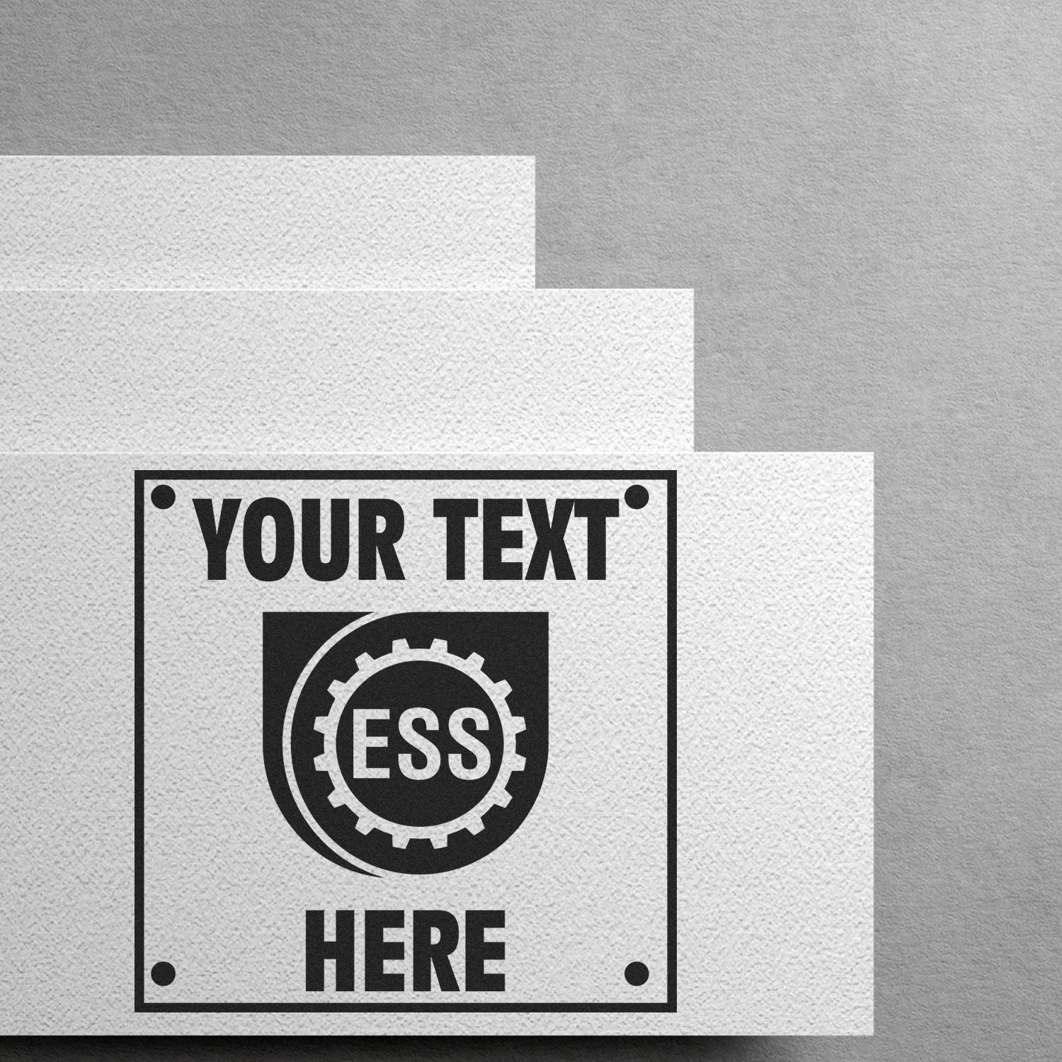 Custom Rubber Stamp Size 1-1/2 x 1-1/2 with YOUR TEXT HERE and ESS logo stamped on white textured paper against a gray background.