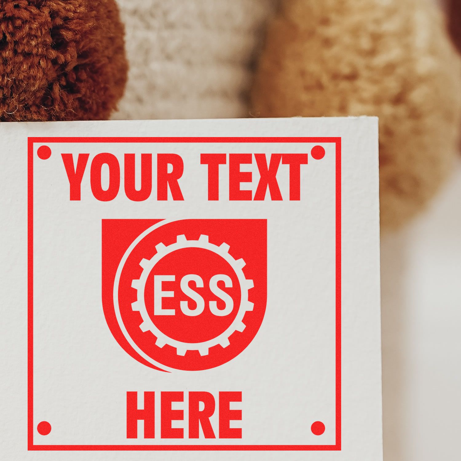 Custom Rubber Stamp Size 5 x 5 in red ink with YOUR TEXT HERE and ESS logo, stamped on white paper against a textured background.