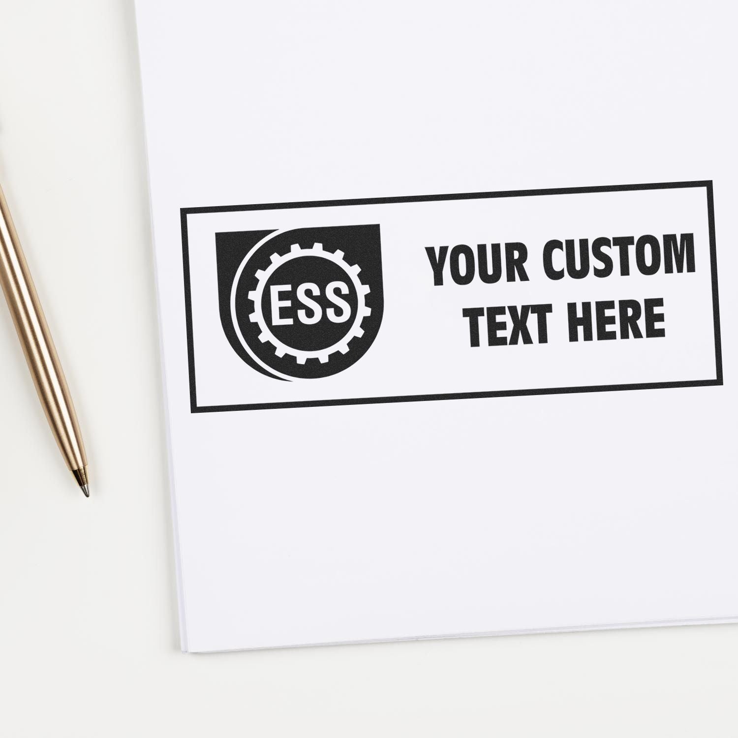 Custom Rubber Stamp Size 1 x 4 imprint on white paper with a pen beside it, displaying ESS logo and placeholder text YOUR CUSTOM TEXT HERE .