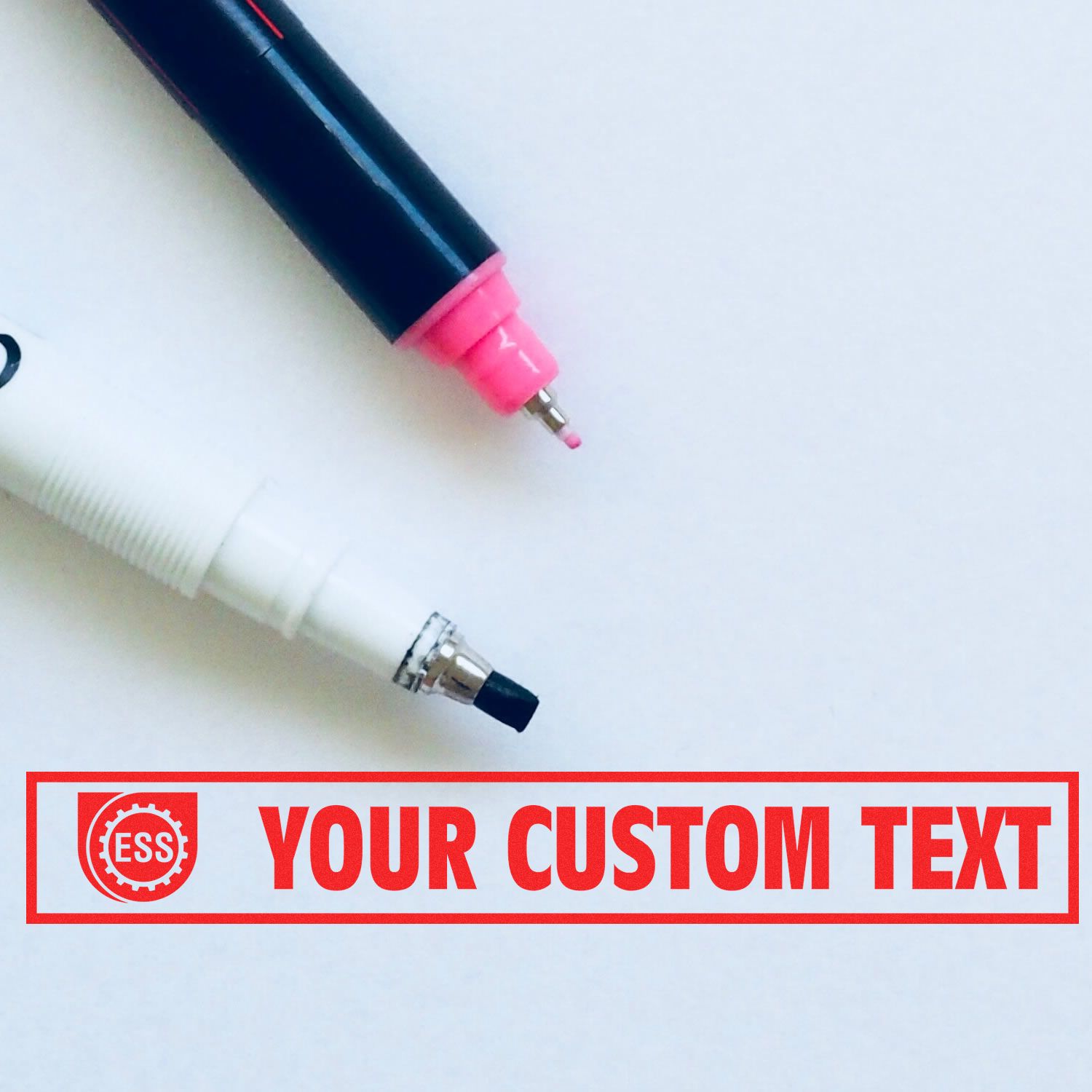 Two markers and a Custom Rubber Stamp Size 1 x 10 with red text YOUR CUSTOM TEXT and ESS logo on a white background.