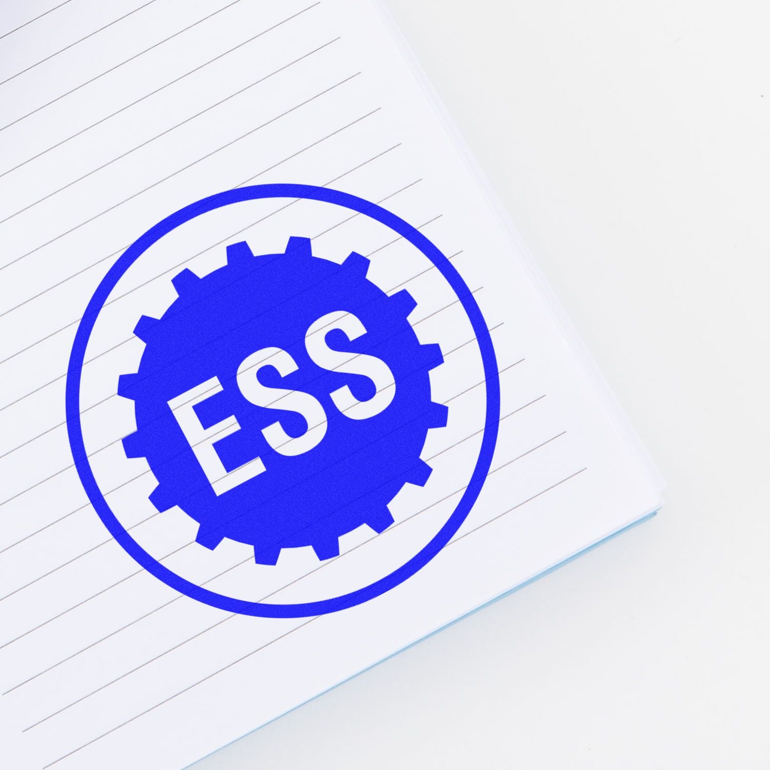 Custom Self Inking Stamp Trodat 46025 Size 1 Diameter imprinting ESS in blue ink on a lined white notebook page.