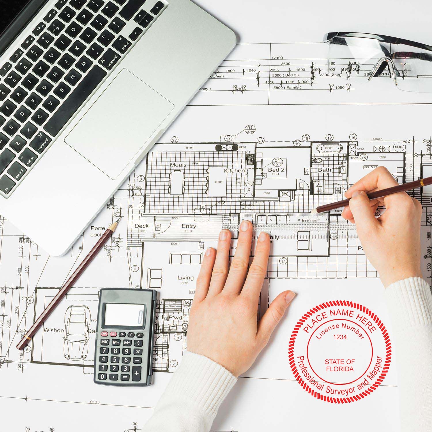 A person using a Digital Florida Land Surveyor Stamp, Electronic Seal for Florida Land Surveyor on architectural plans, with a laptop and calculator nearby.