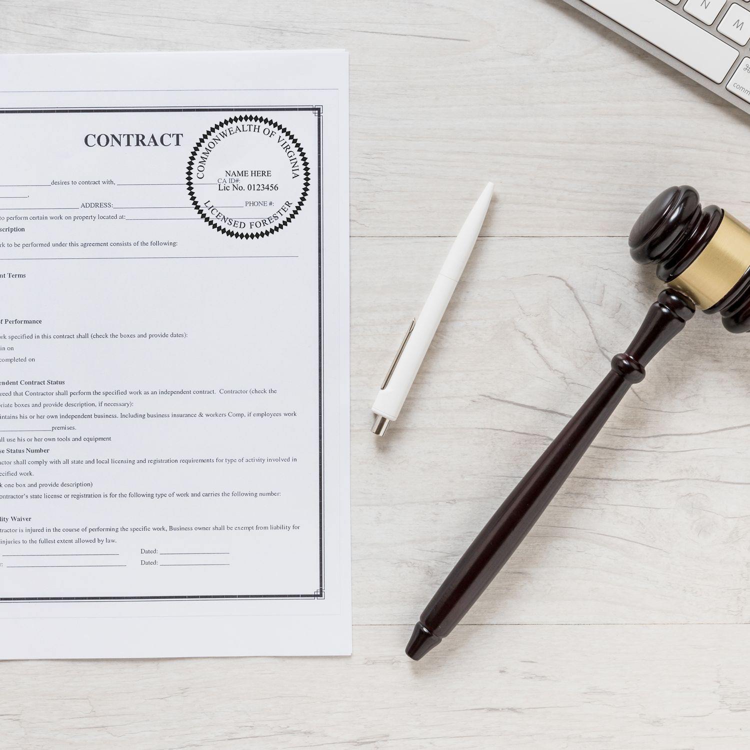 Forester Slim Pre-Inked Rubber Stamp of Seal used on a contract document, placed on a desk with a pen, gavel, and keyboard nearby.