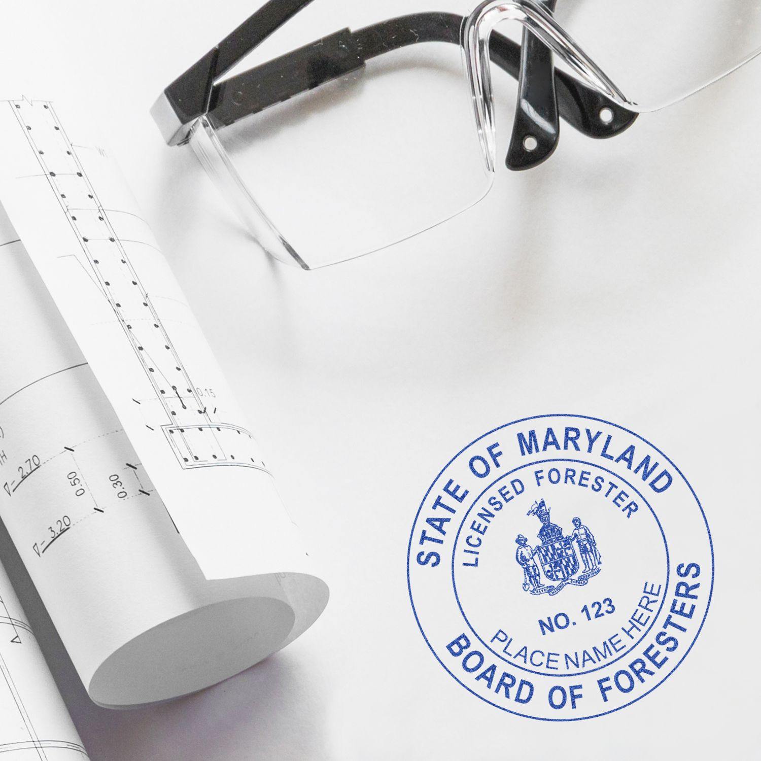 Forester Regular Rubber Stamp of Seal on a white surface next to rolled-up blueprints and safety glasses.