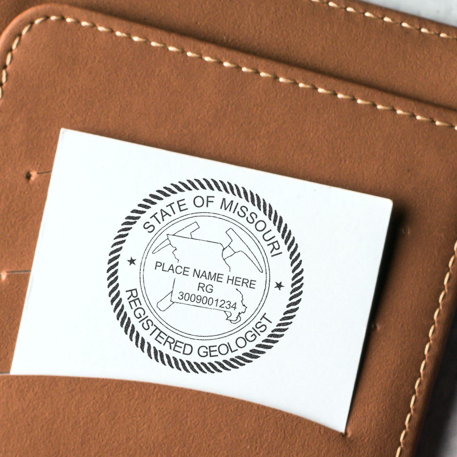 Geologist Regular Rubber Stamp of Seal on white card with State of Missouri Registered Geologist text, placed on a brown leather surface.