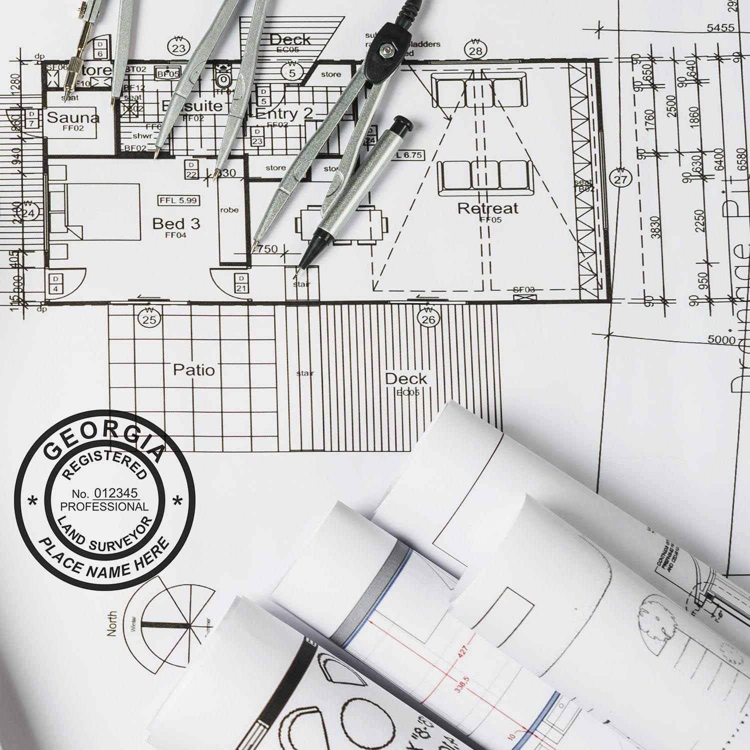 Blueprints with a Digital Georgia Land Surveyor Stamp, Electronic Seal for Georgia Land Surveyor, and drafting tools on a desk.