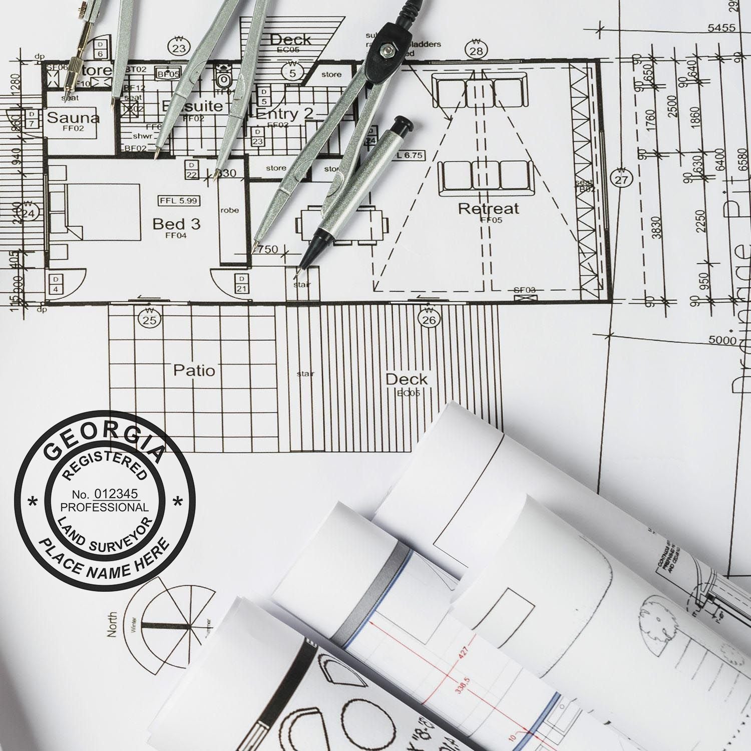 Self Inking Georgia Land Surveyor Stamp in use on architectural blueprints with drafting tools and rolled-up plans in the background.