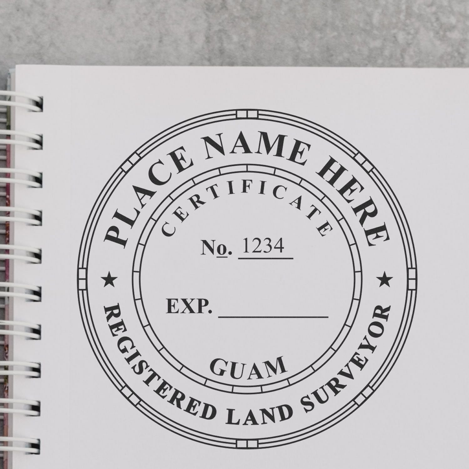 Guam Land Surveyor Seal Stamp, GU PLS Stamp, on a white notebook page with a spiral binding, displaying customizable text fields.