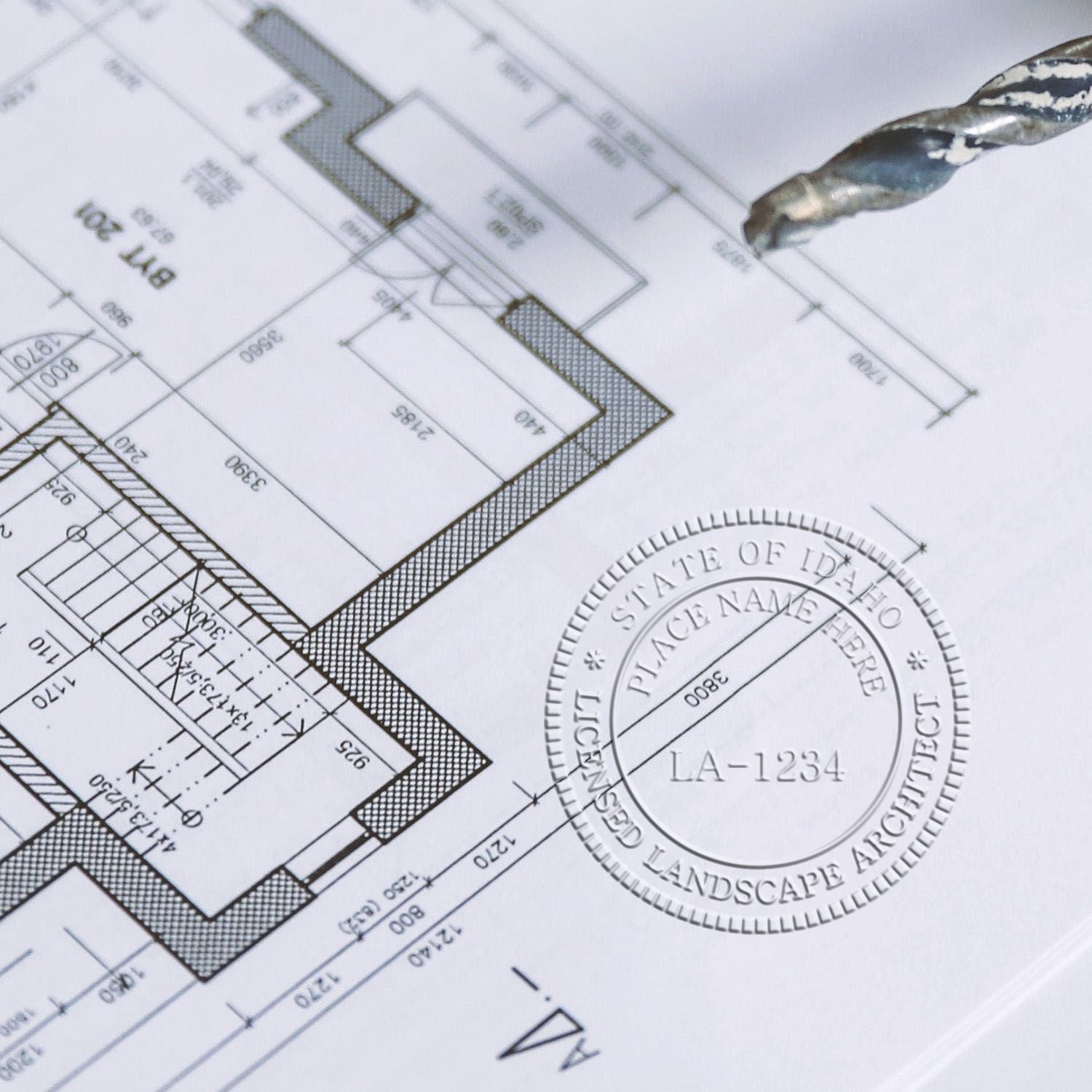 A lifestyle photo showing a stamped image of the Soft Pocket Idaho Landscape Architect Embosser on a piece of paper