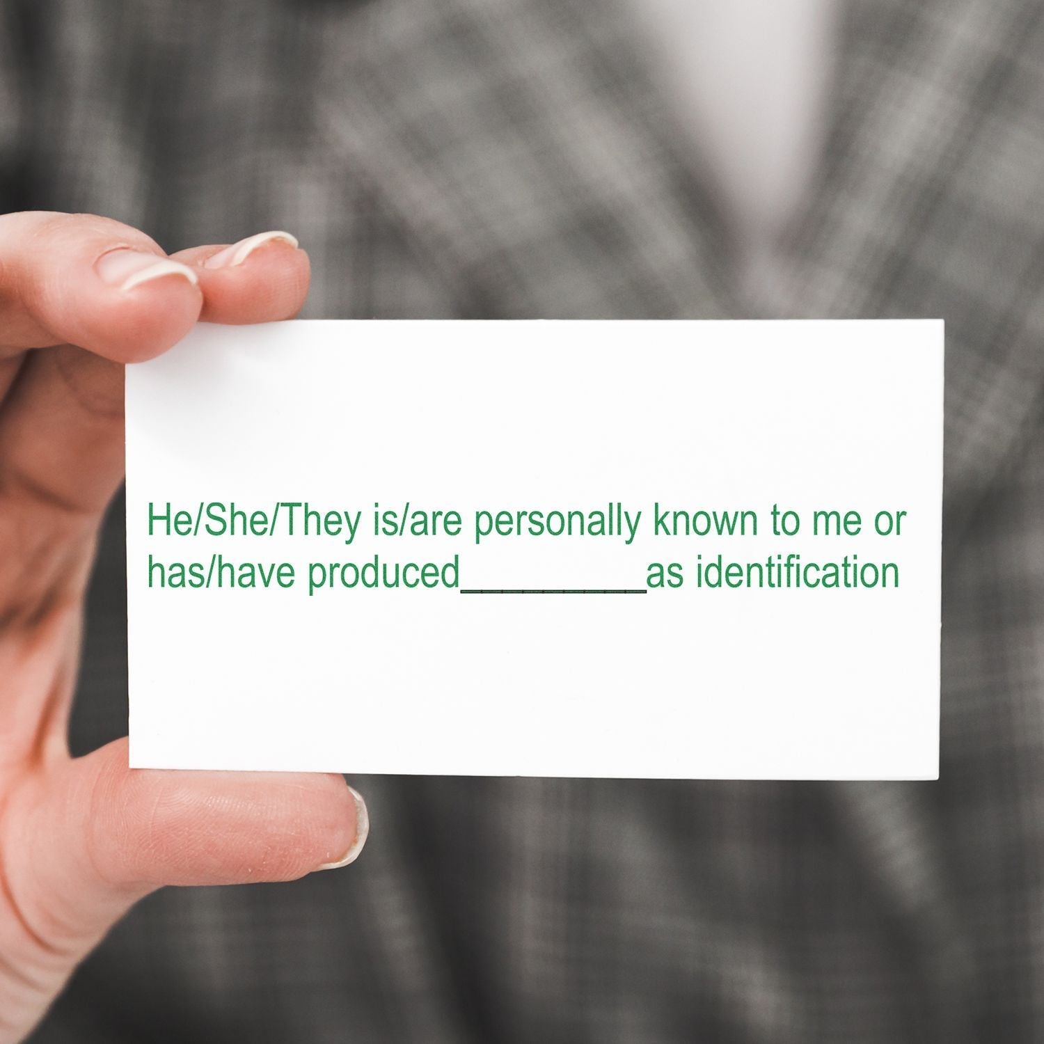 A hand holding a card with green text and blank space for identification, using the Regular Identification Stamp.