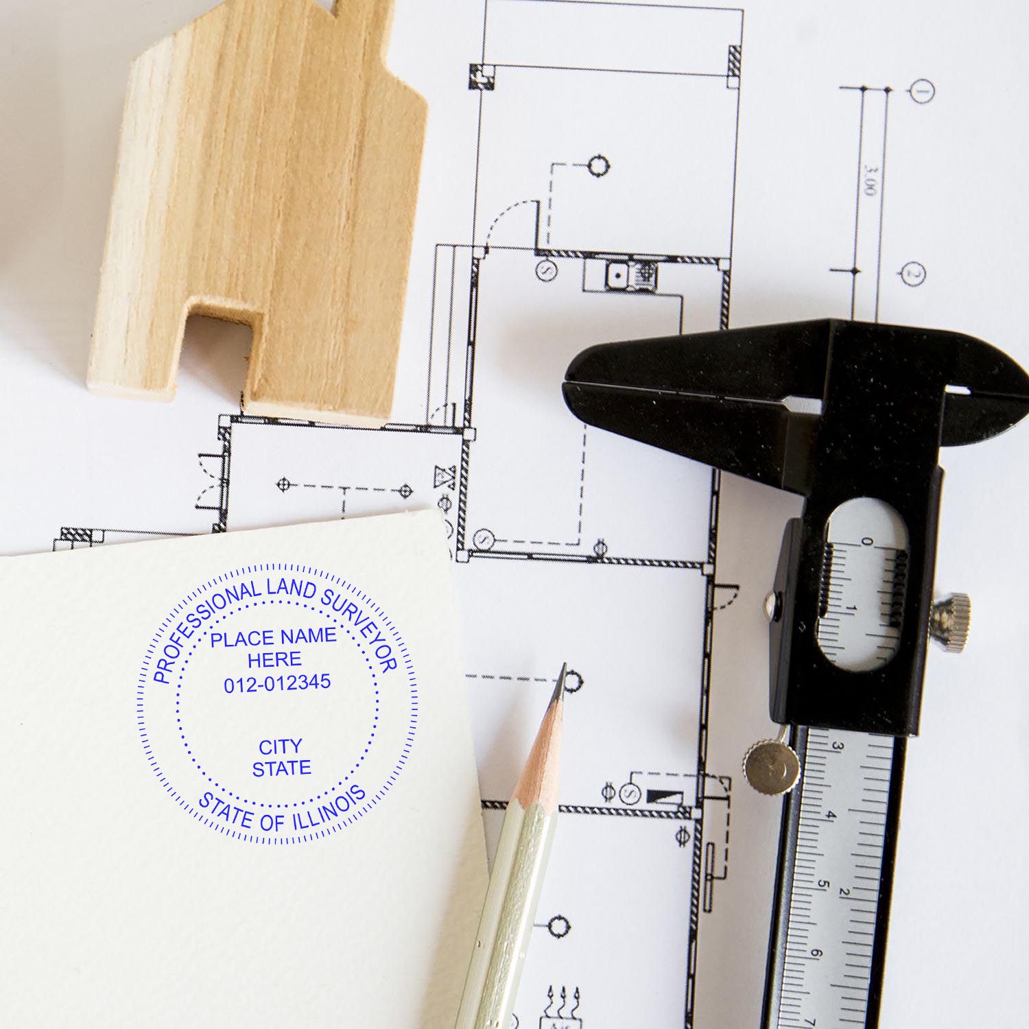 Illinois Land Surveyor Seal Stamp on paper with architectural plans, a wooden house model, a pencil, and a caliper nearby.