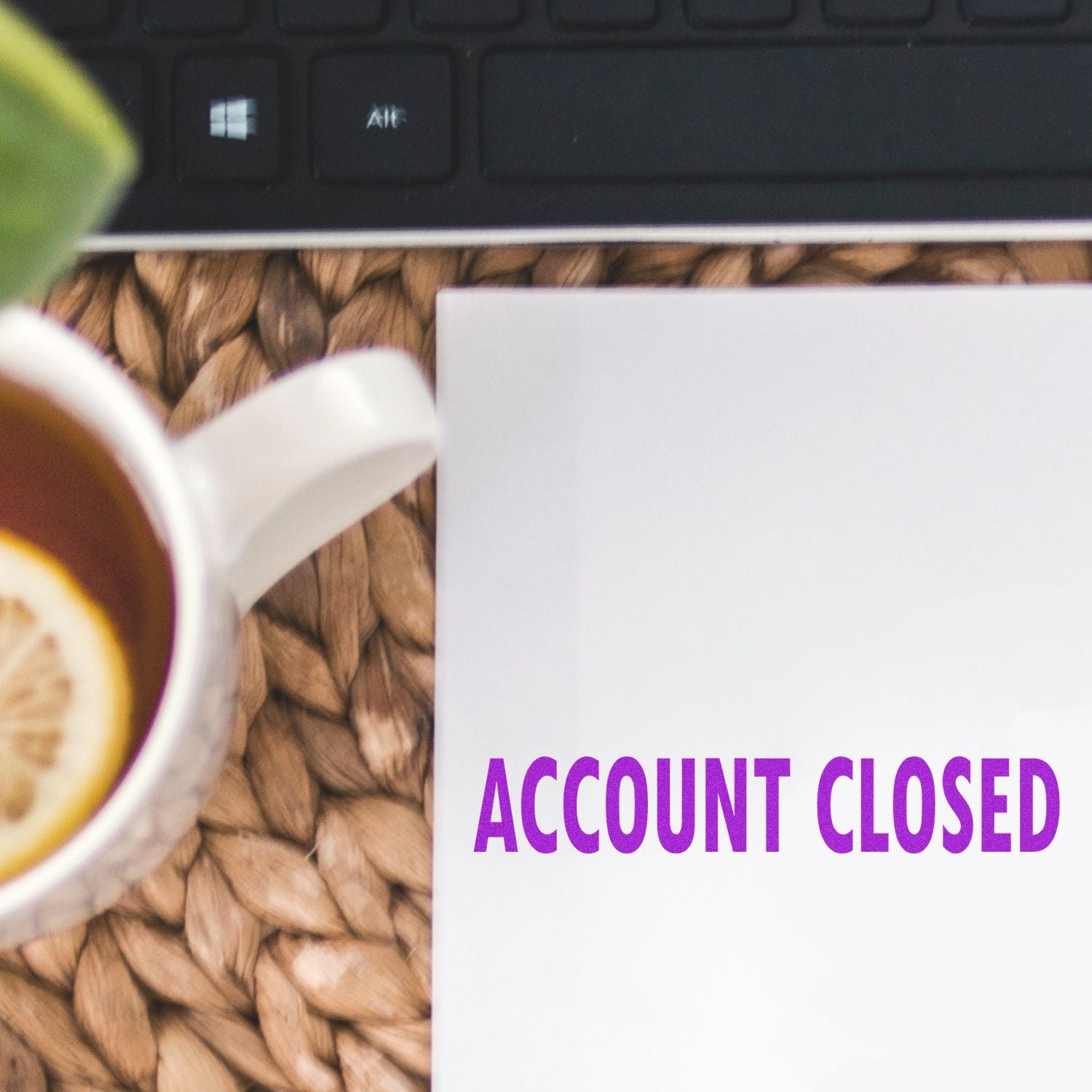 Large Account Closed Rubber Stamp marking a white paper with ACCOUNT CLOSED in purple ink, next to a cup of tea and a keyboard.