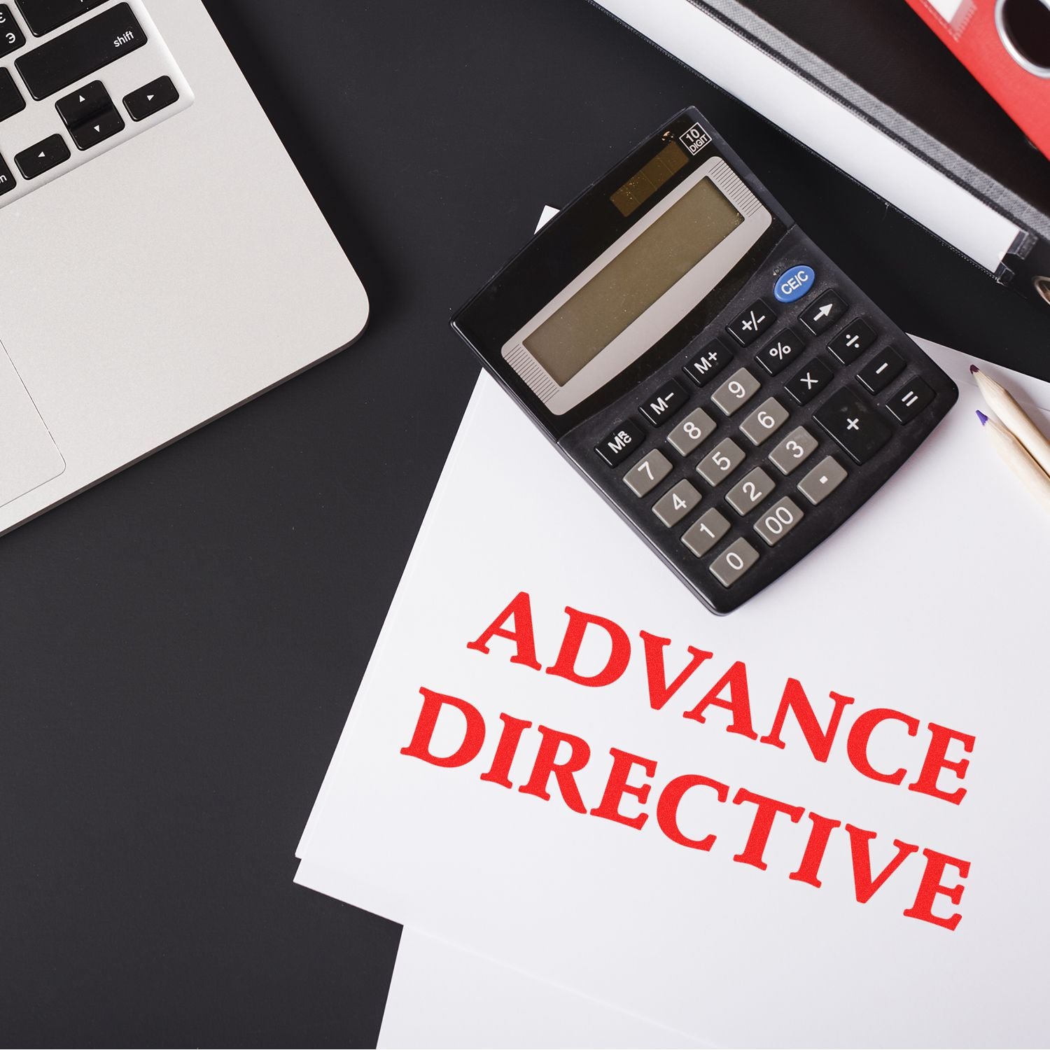 Large Self Inking Advance Directive Stamp used on documents, placed next to a calculator, laptop, and pencil on a black desk.