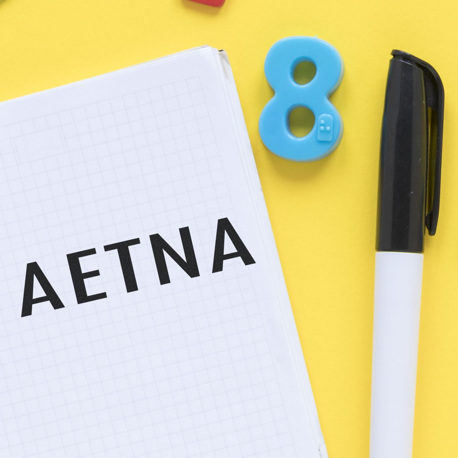 Medical Aetna rubber stamp on a notebook with a pen and a blue number eight on a yellow background.