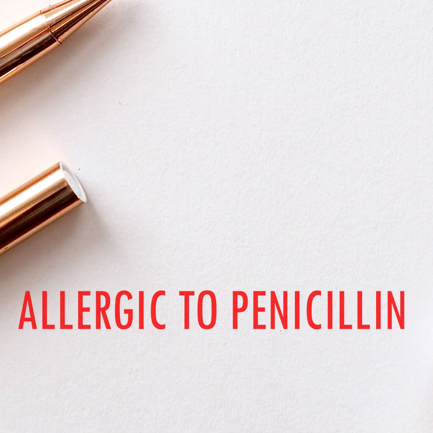 Large Self Inking Allergic To Penicillin Stamp in use, displaying bold red text ALLERGIC TO PENICILLIN on white paper next to a gold pen.