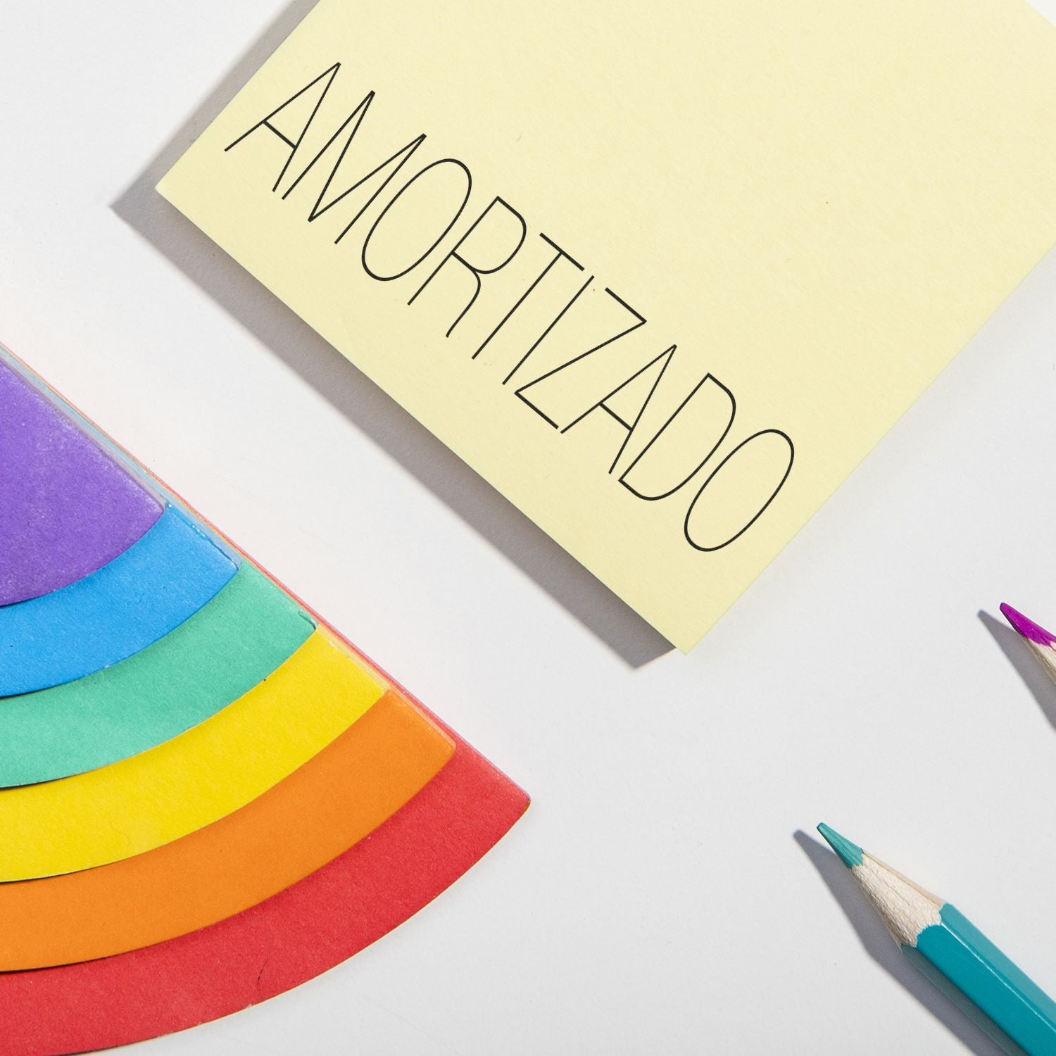 Large Pre-Inked Amortizado Stamp in use on a yellow paper, surrounded by colorful paper pieces and pencils.