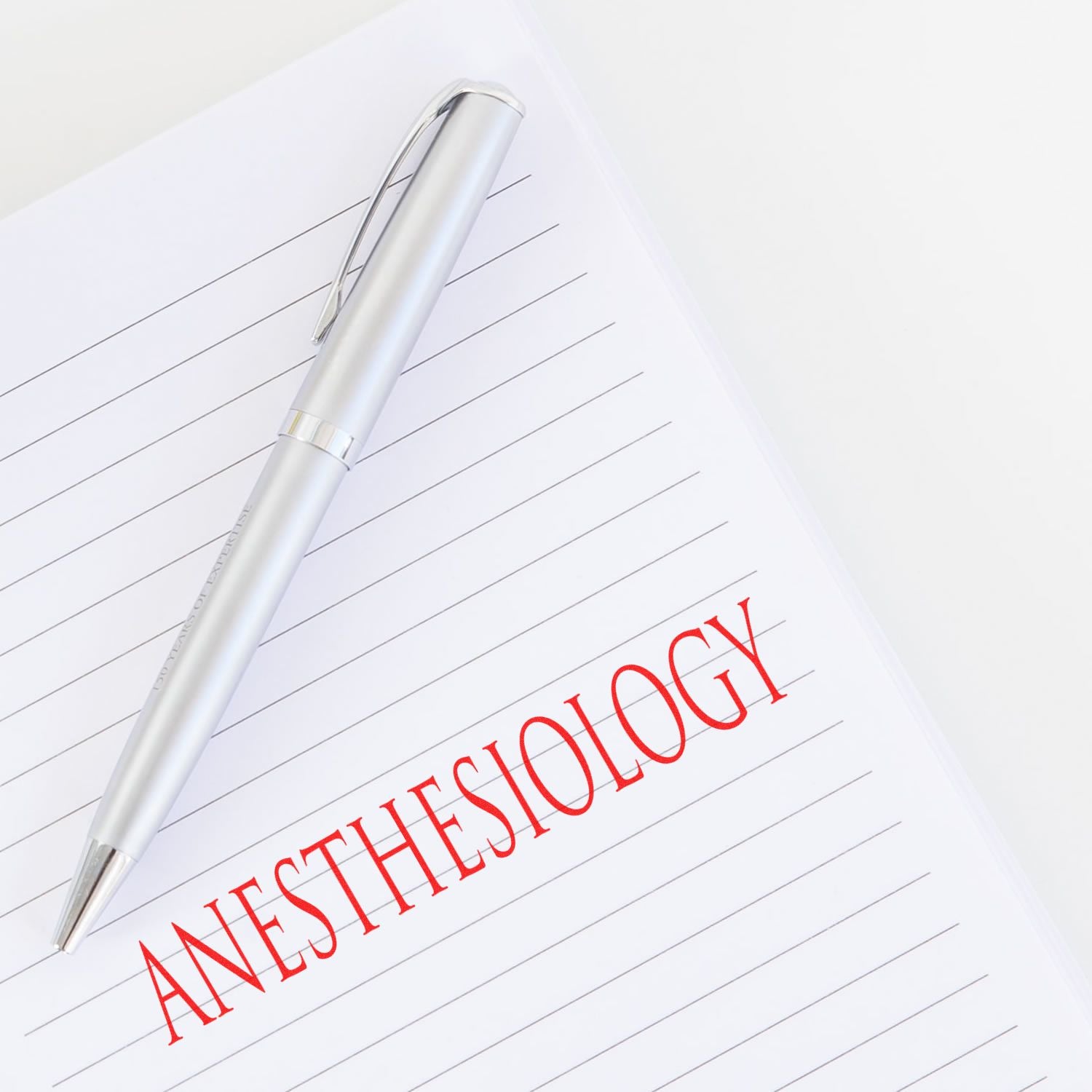 Anesthesiology rubber stamp imprint in red ink on lined paper with a silver pen placed diagonally on the page.