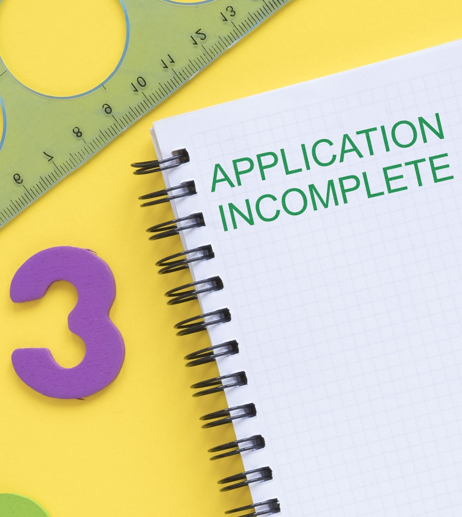 A notebook with APPLICATION INCOMPLETE stamped in green, next to a ruler and a purple number 3 on a yellow background.