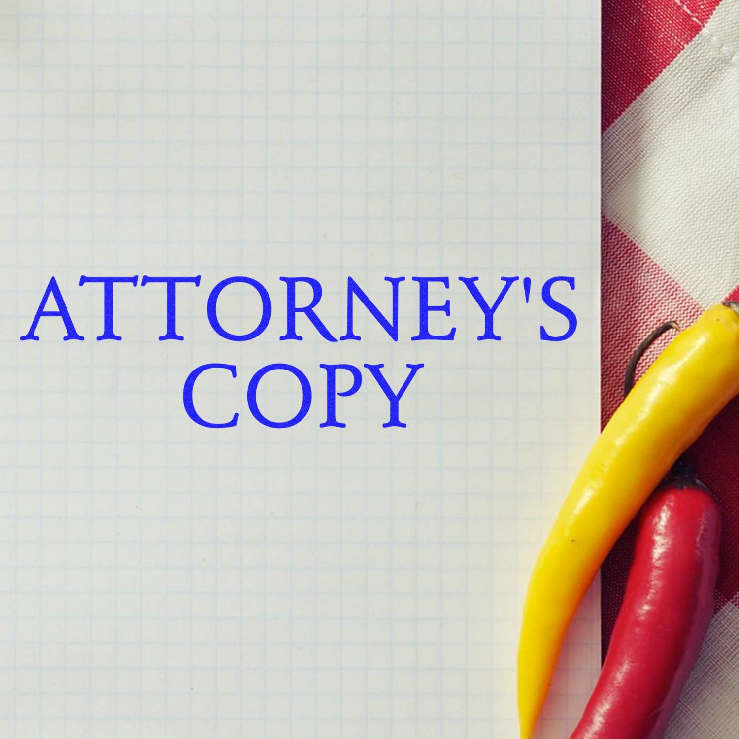 Large Attorneys Copy Rubber Stamp in use on a grid paper with a red and white checkered cloth and two chili peppers beside it.