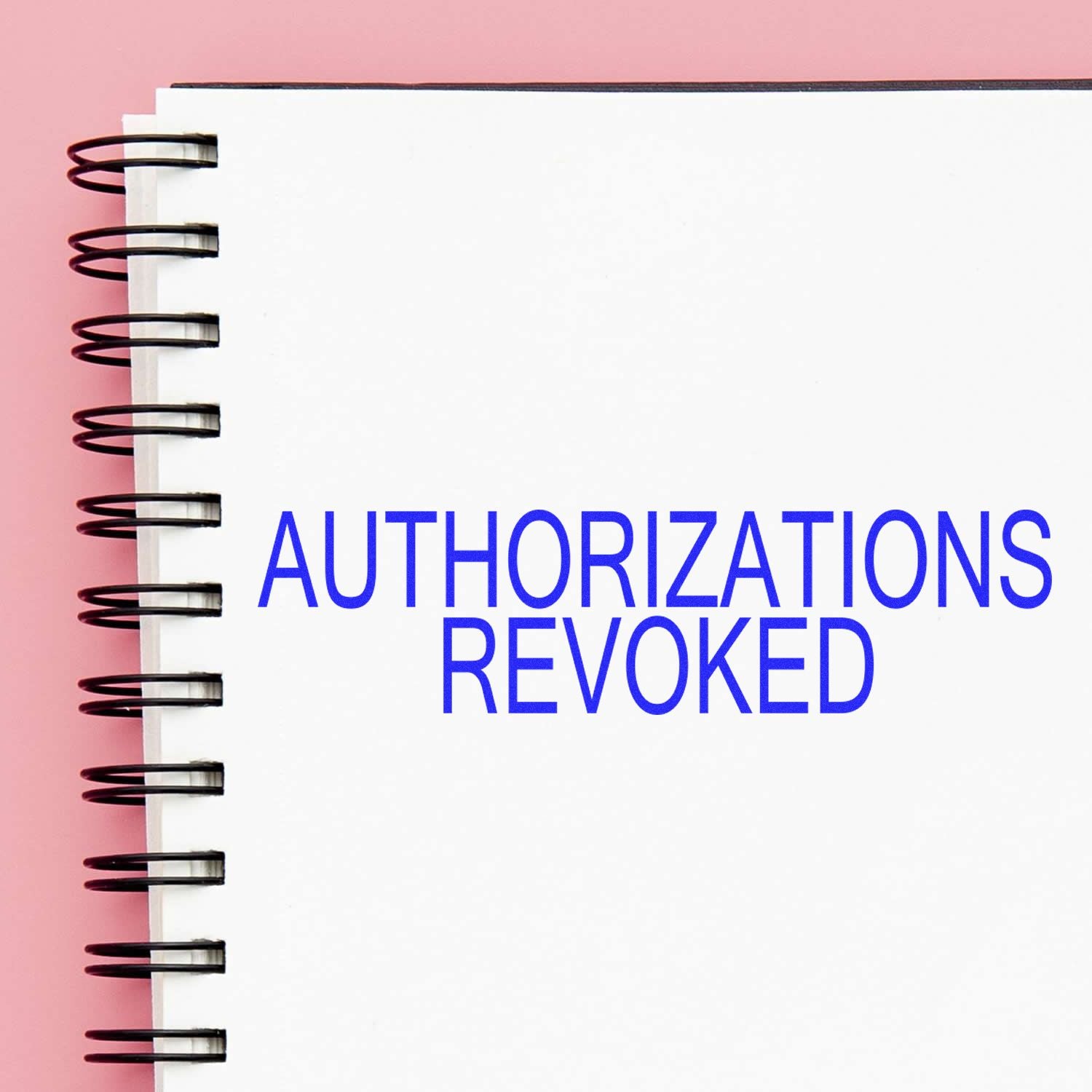 Notebook with spiral binding displaying a blue 'Authorizations Revoked' rubber stamp on a white page against a pink background.