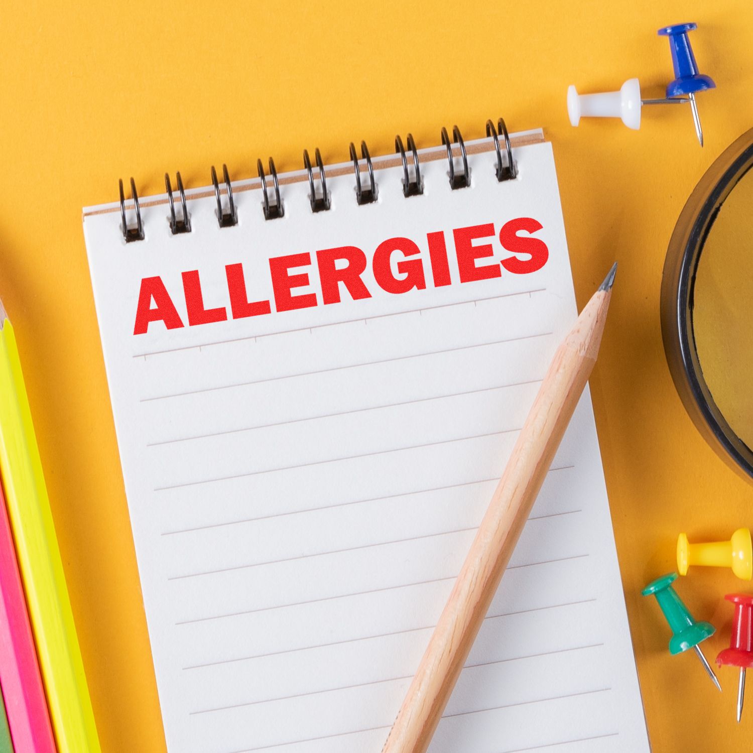 A notebook with ALLERGIES stamped in red using the Large Self Inking Bold Allergies Stamp, surrounded by colorful pins and a pencil.