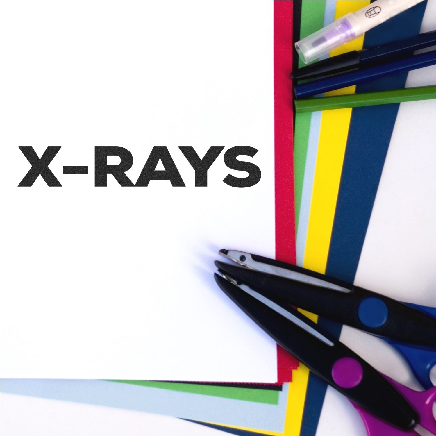 Bold X-Rays rubber stamp impression on white paper, surrounded by colorful sheets, scissors, and pens.