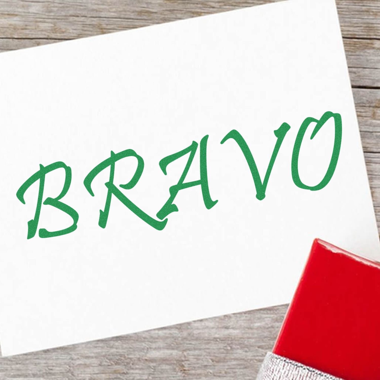 Self Inking Bravo Stamp in use, displaying the word BRAVO in green ink on a white card, with the stamp partially visible.