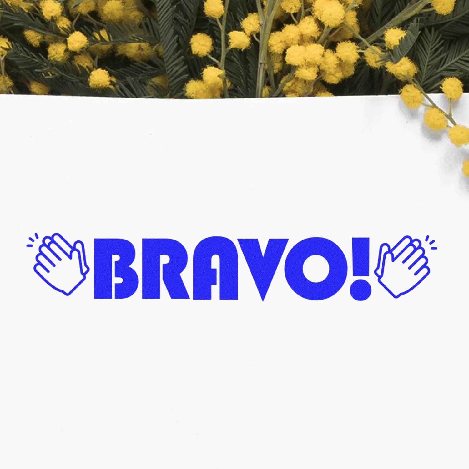 Large Bravo with Hands Rubber Stamp in blue ink on white paper, surrounded by yellow flowers in the background.