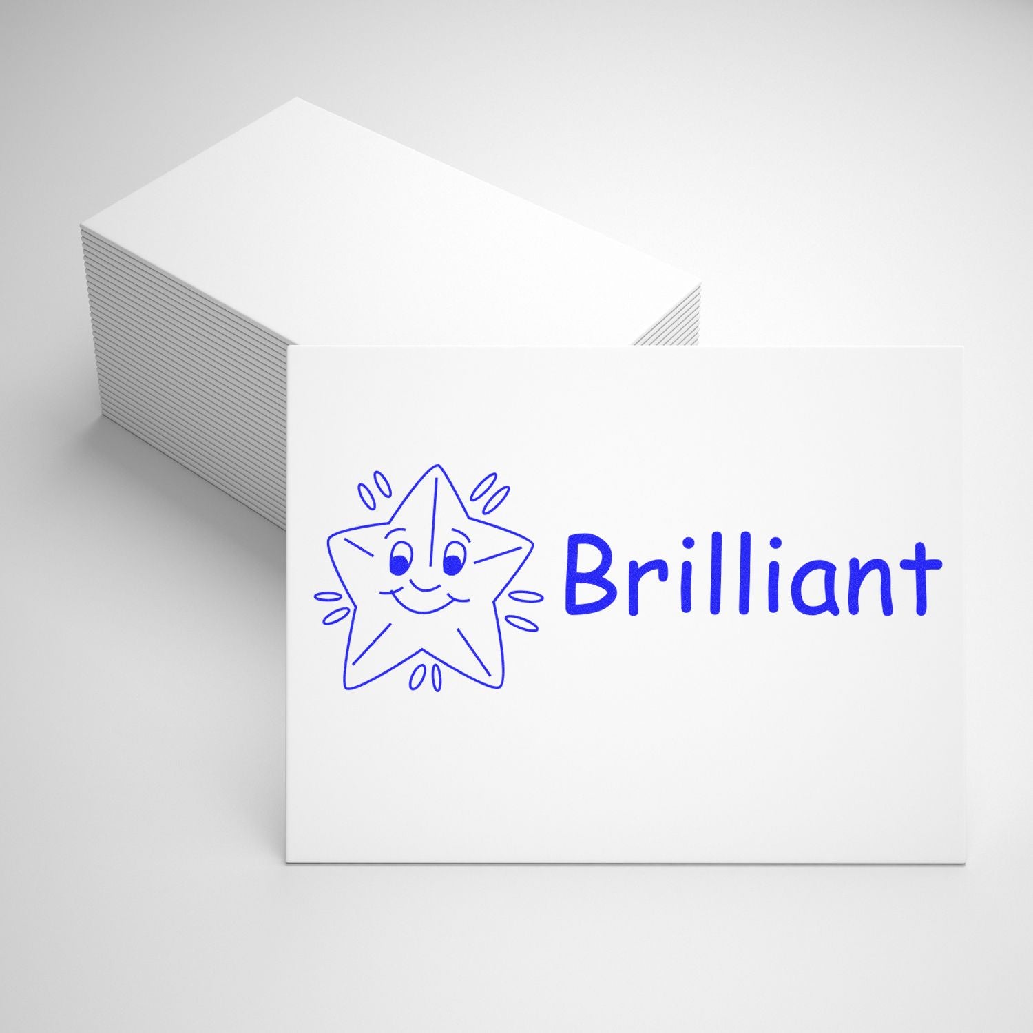 A stack of white cards with one card stamped with a blue star and the word Brilliant using the Large Self Inking Brilliant Stamp.